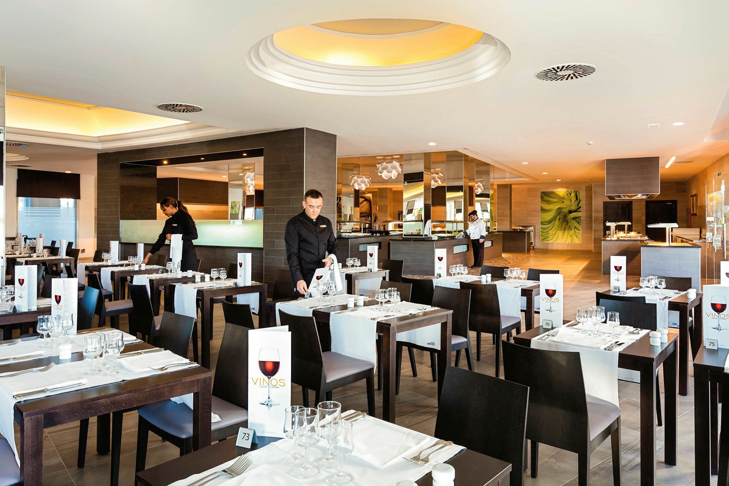 En restaurant med stilfullt dekkede bord og servitører som gjør klart for gjester. (AI-generert tekst)