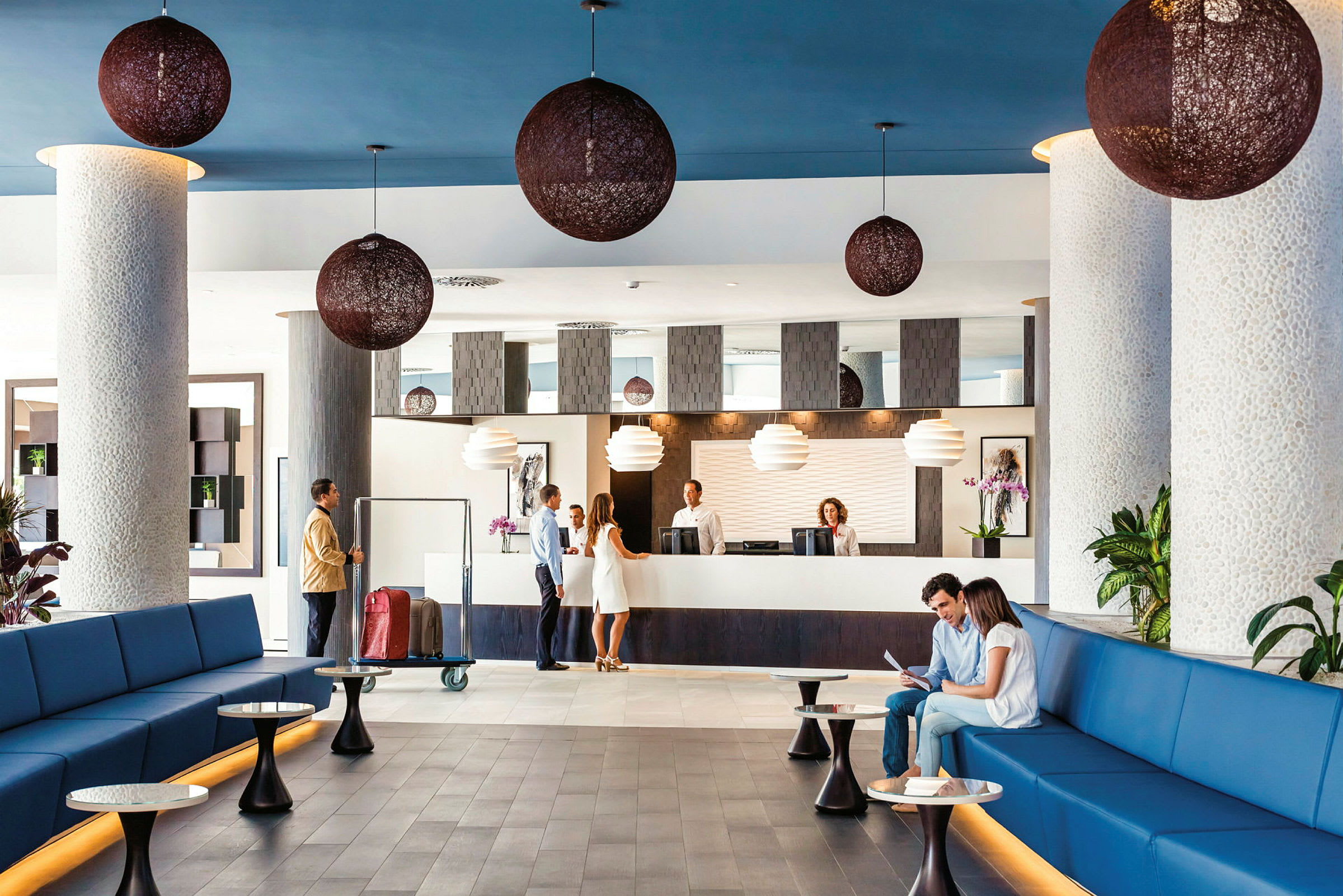 Lys hotellobby med sitteplasser, resepsjon og dekorativ belysning. (AI-generert tekst)