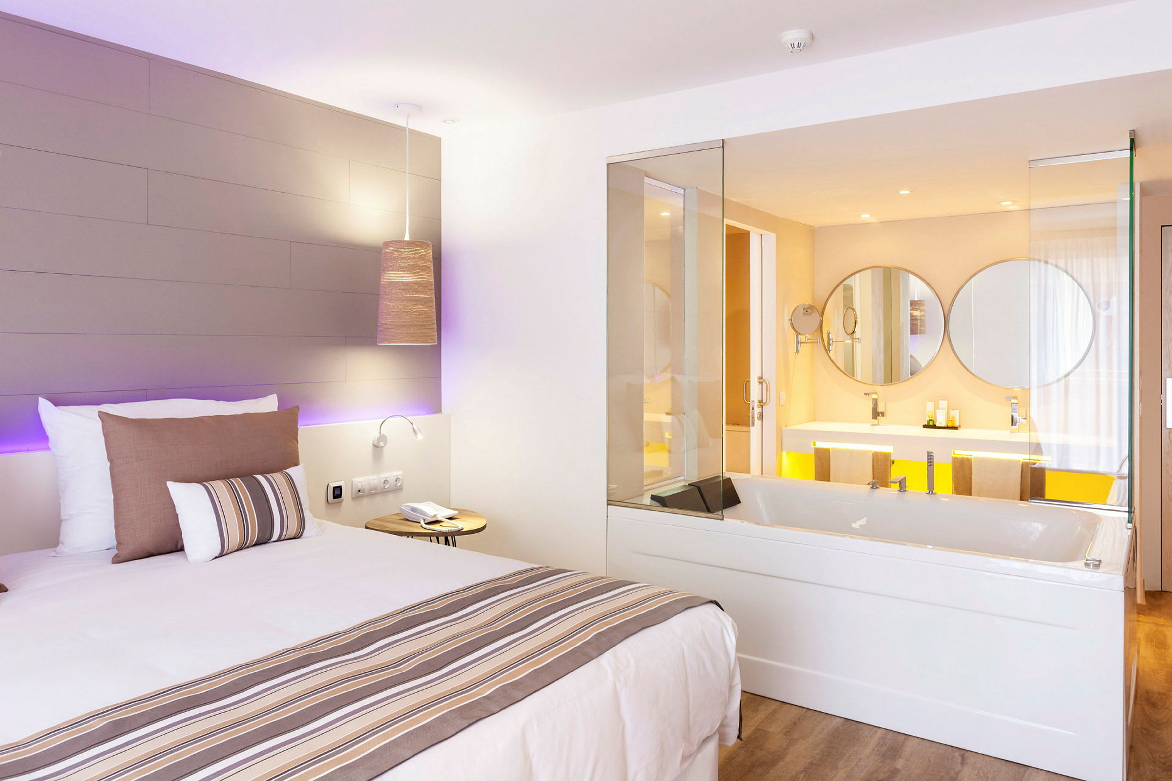 Hotellrom med en seng og et innebygd boblebad som vender mot et bad. (AI-generert tekst)