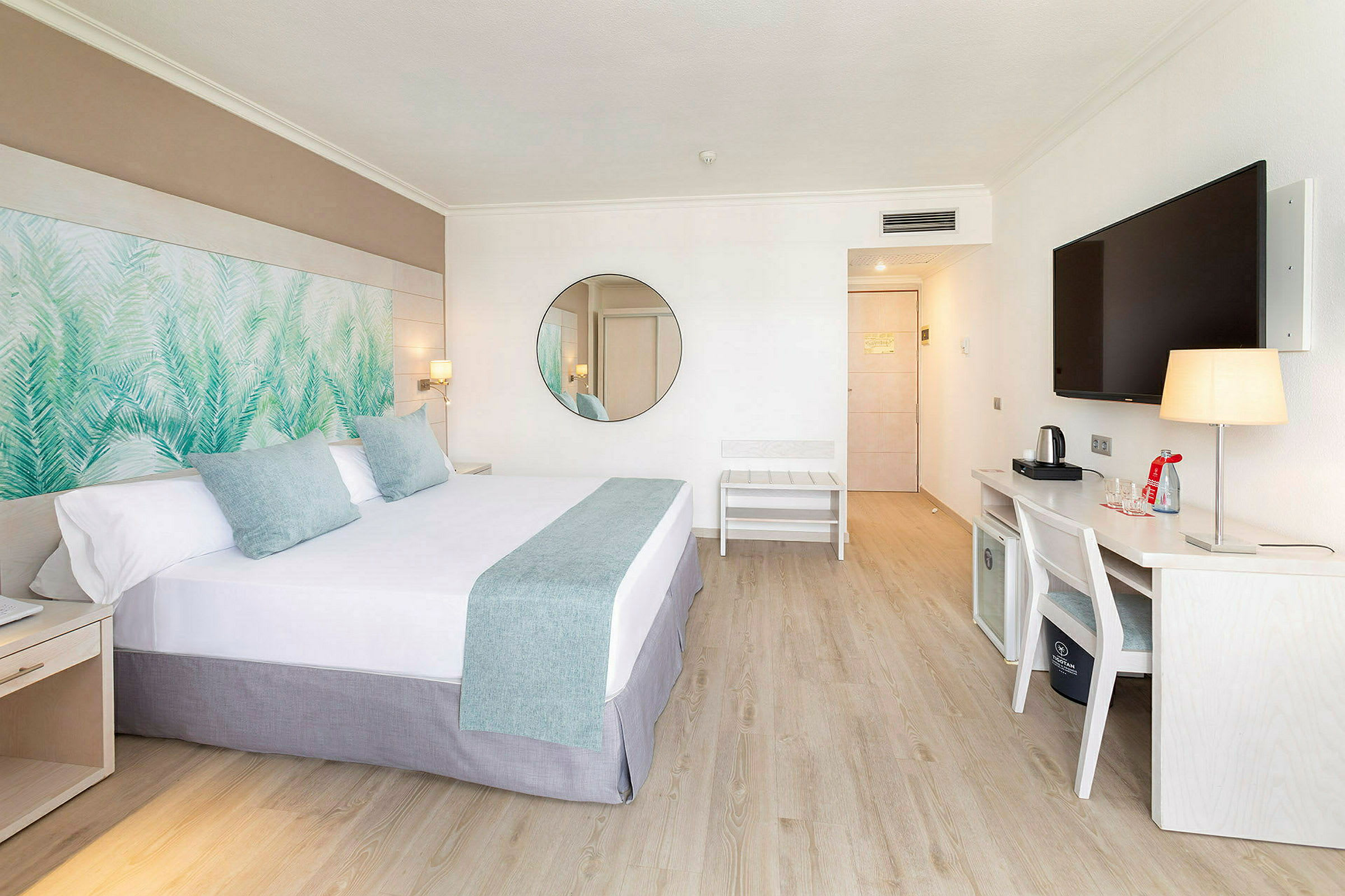 Moderne hotellrom med en dobbeltseng, veggdekorasjon, skrivebord og en TV. (AI-generert tekst)