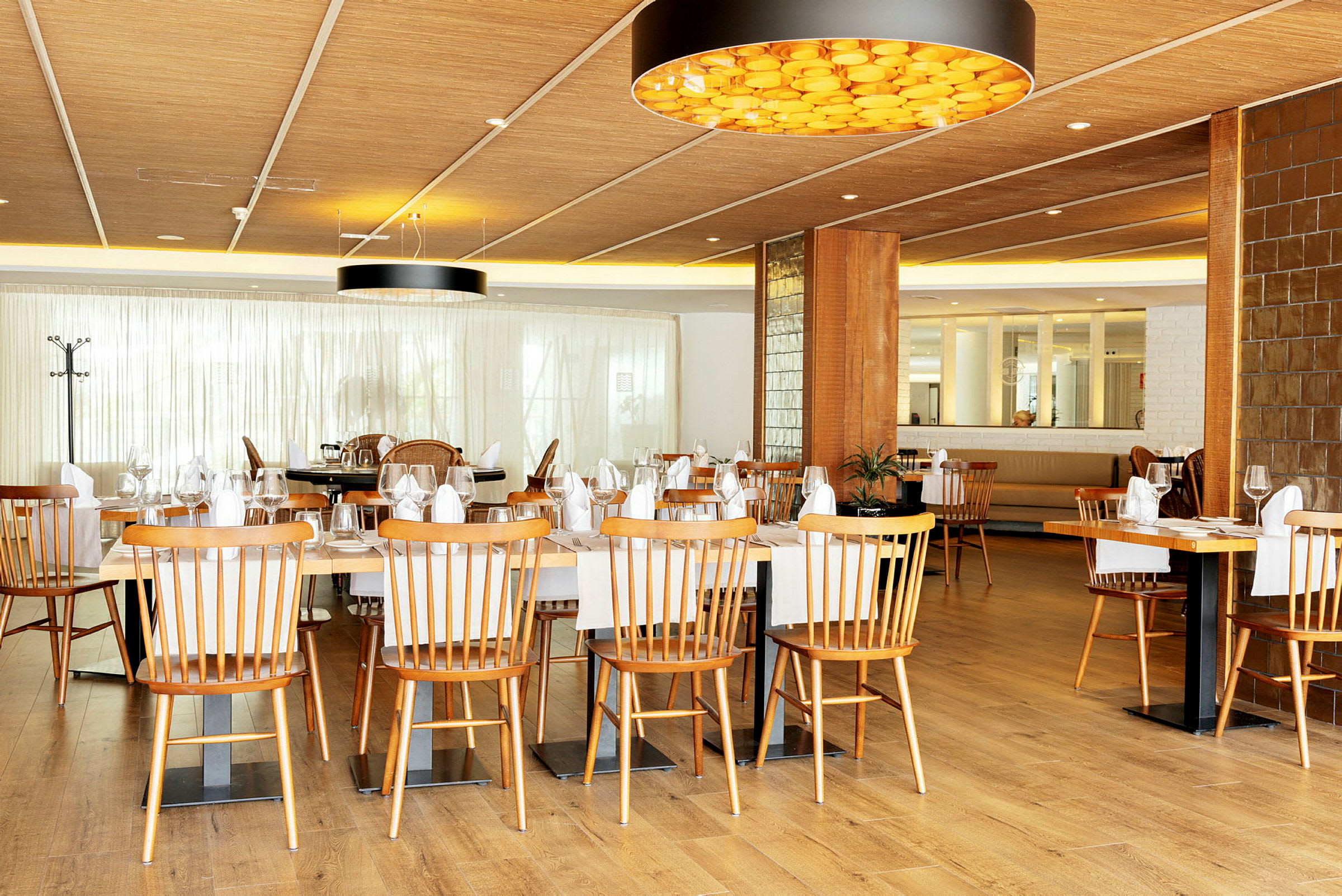 En lys restaurant med trestoler og dekte bord. (AI-generert tekst)