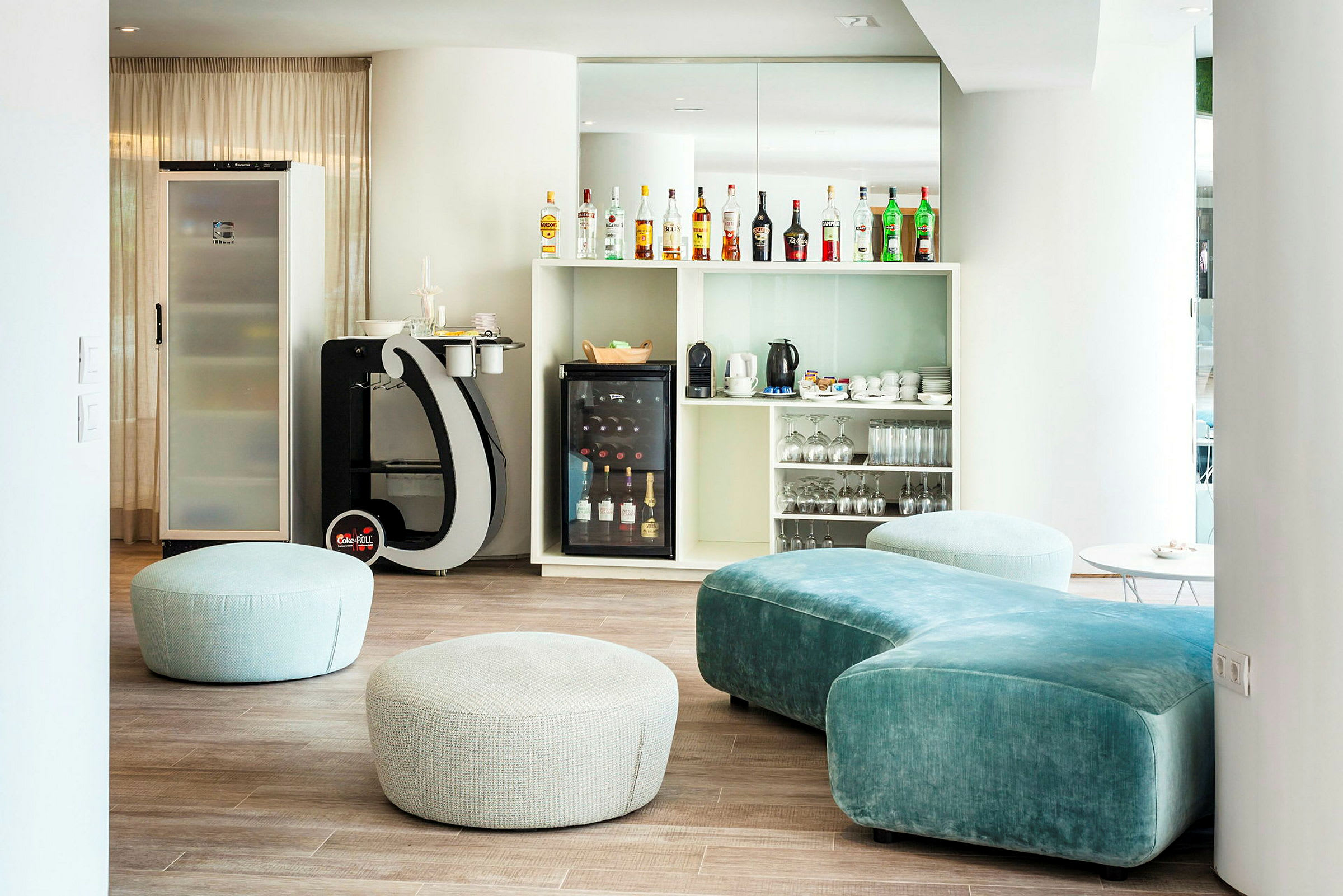 Loungeområde med sittpuffer, sofa og en bar med drikker. (AI-generert tekst)