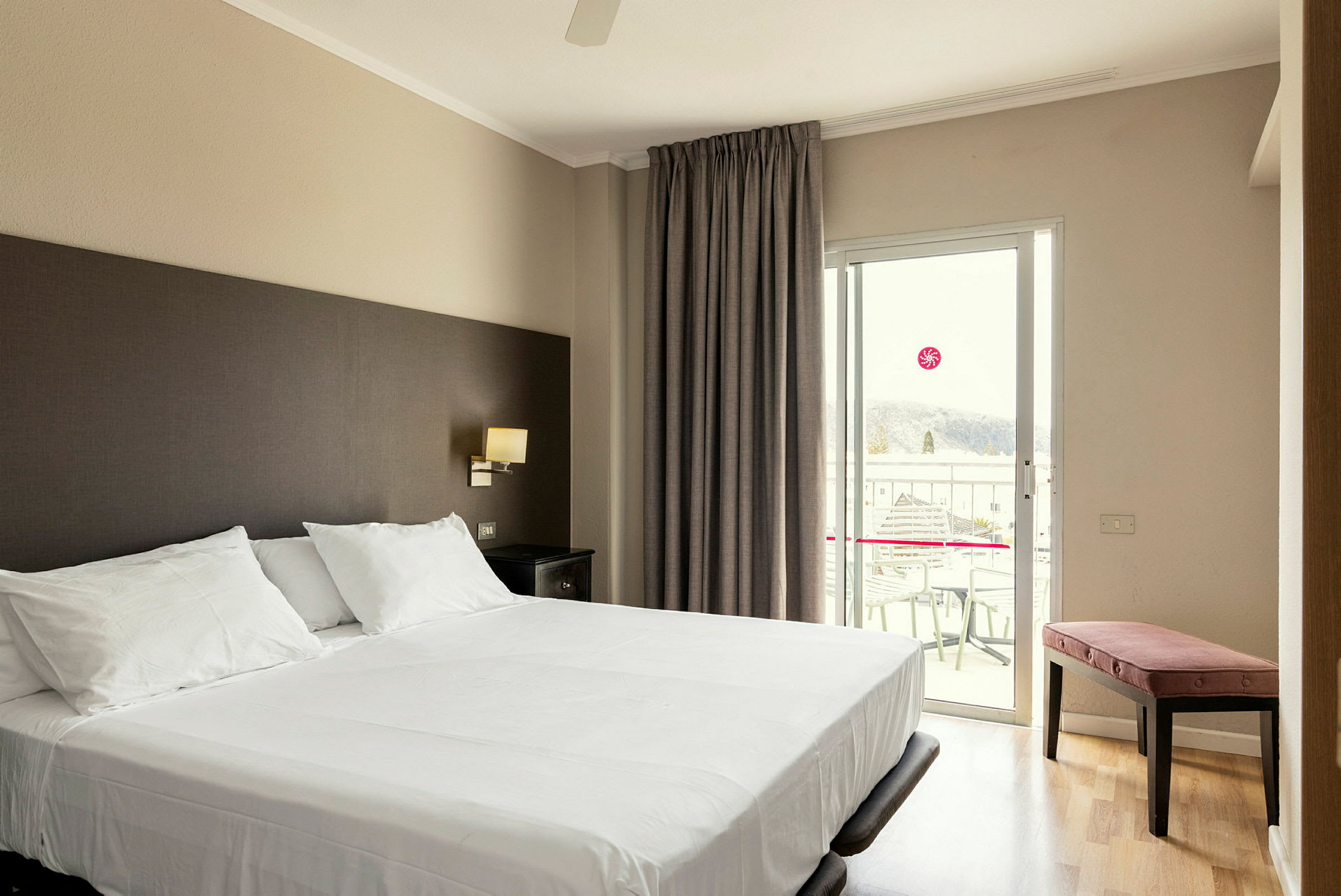 Hotellrom med en dobbeltseng og balkong. (AI-generert tekst)