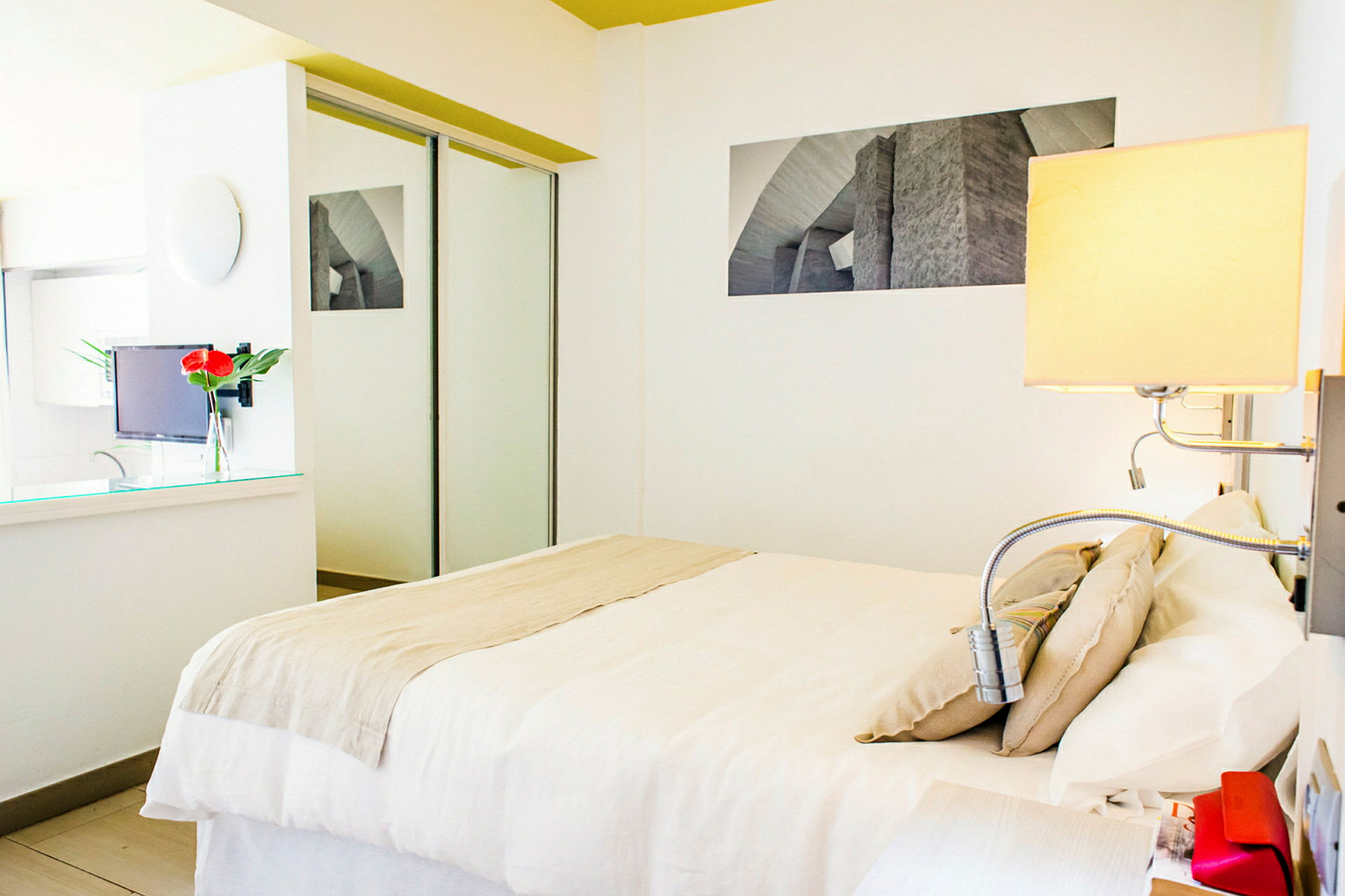 Et moderne og lyst hotellrom med hvitt interiør, en dobbeltseng og et innebygd speilgarderobeskap. (AI-generert tekst)