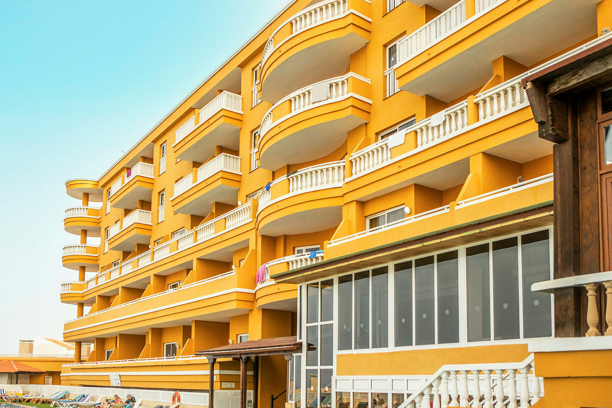 Et gult hotell med mange balkonger i flere etasjer. (AI-generert tekst)
