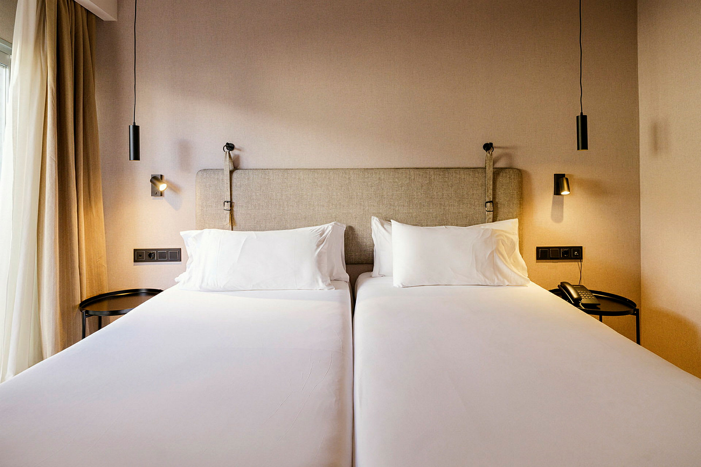 To enkeltsenger i et hotellrom med sengelamper. (AI-generert tekst)