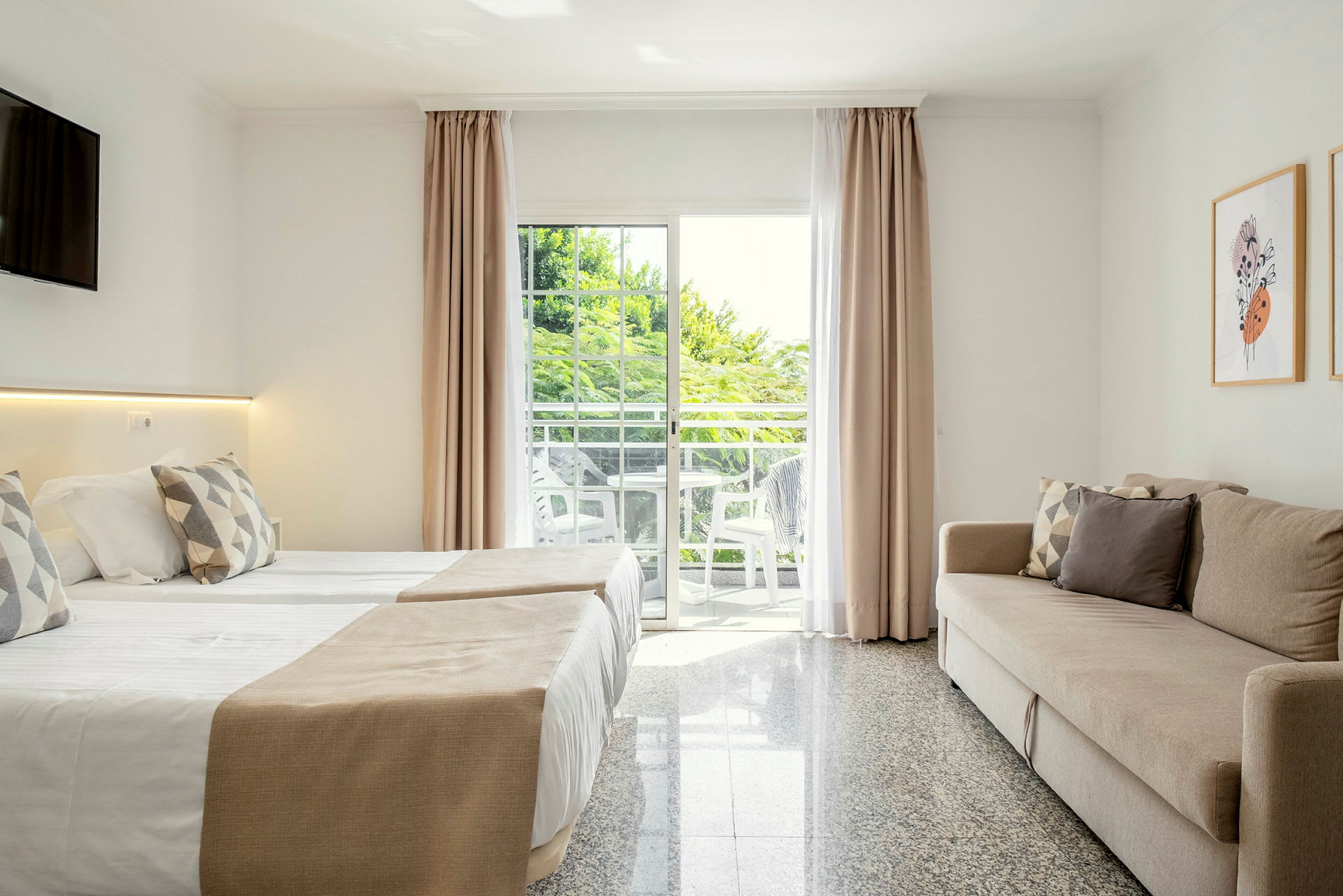 Moderne hotellrominteriør med en sovesofa, to senger og en balkong med utsikt. (AI-generert tekst)