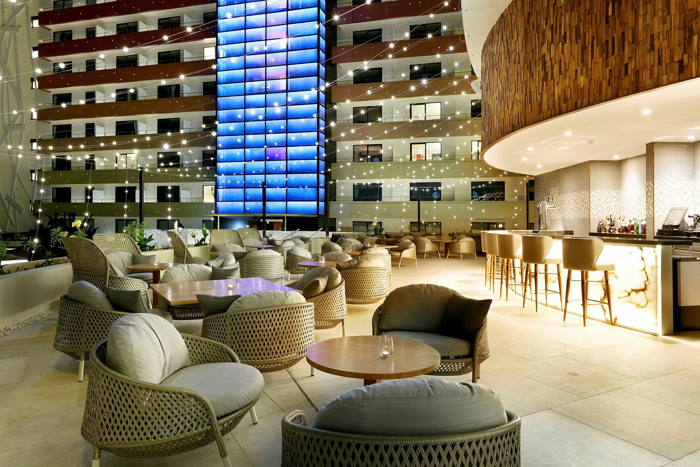 En opplyst hotellbar og sittegrupper på en terrasse om kvelden. (AI-generert tekst)