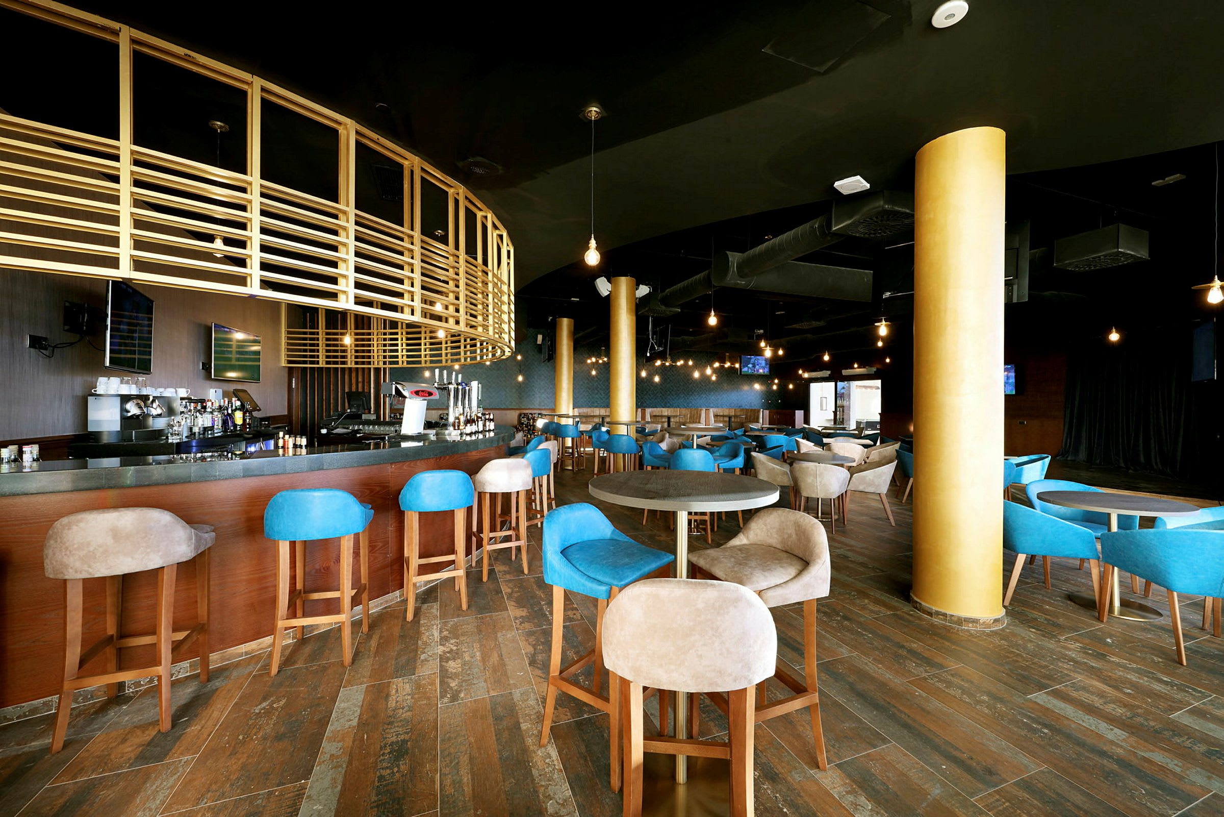 Interiør av en moderne bar med treinnredning og blå samt beige stoler. (AI-generert tekst)