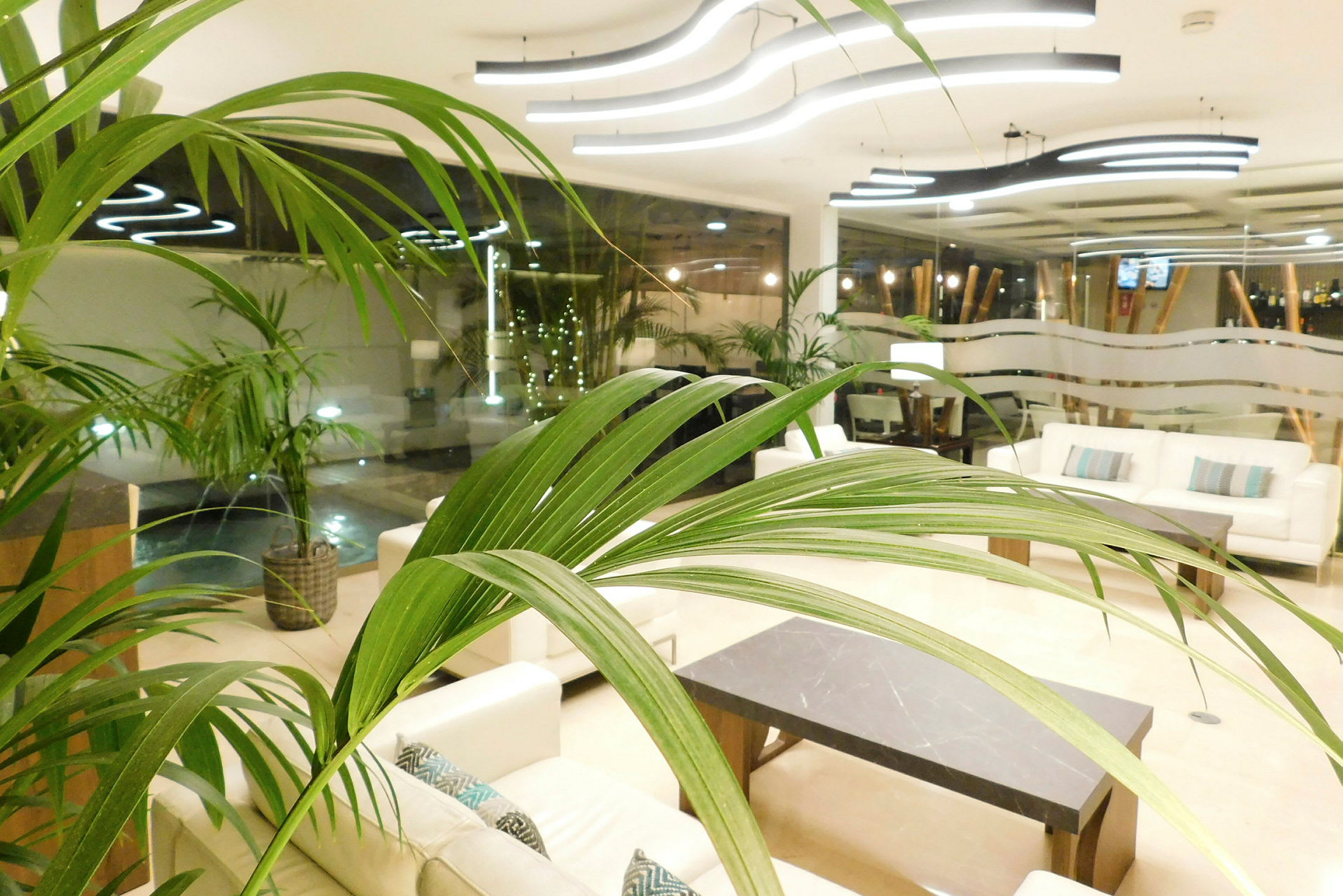 Lys og moderne lobby med sofaer og bord, med frodige planter og elegant belysning. (AI-generert tekst)