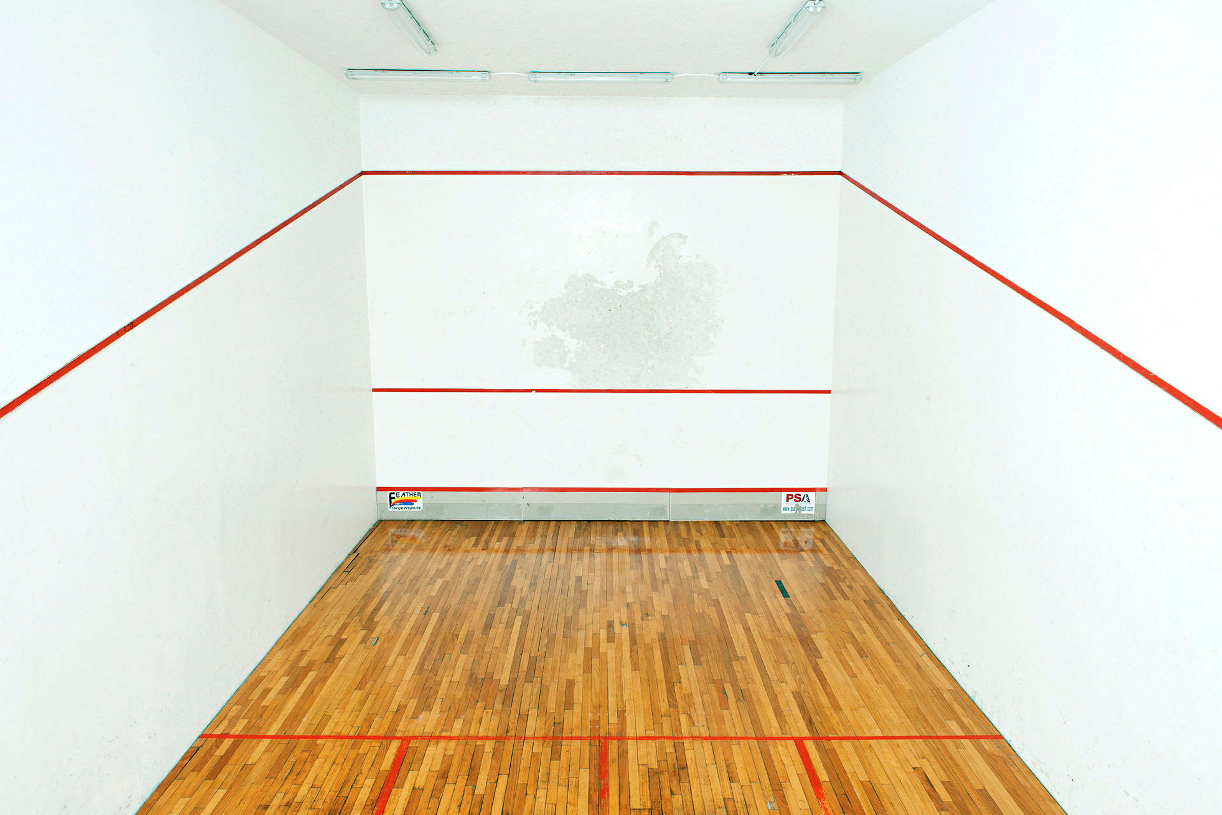 Bilde av en squashbane med tregulv og hvite vegger markert med røde linjer. (AI-generert tekst)