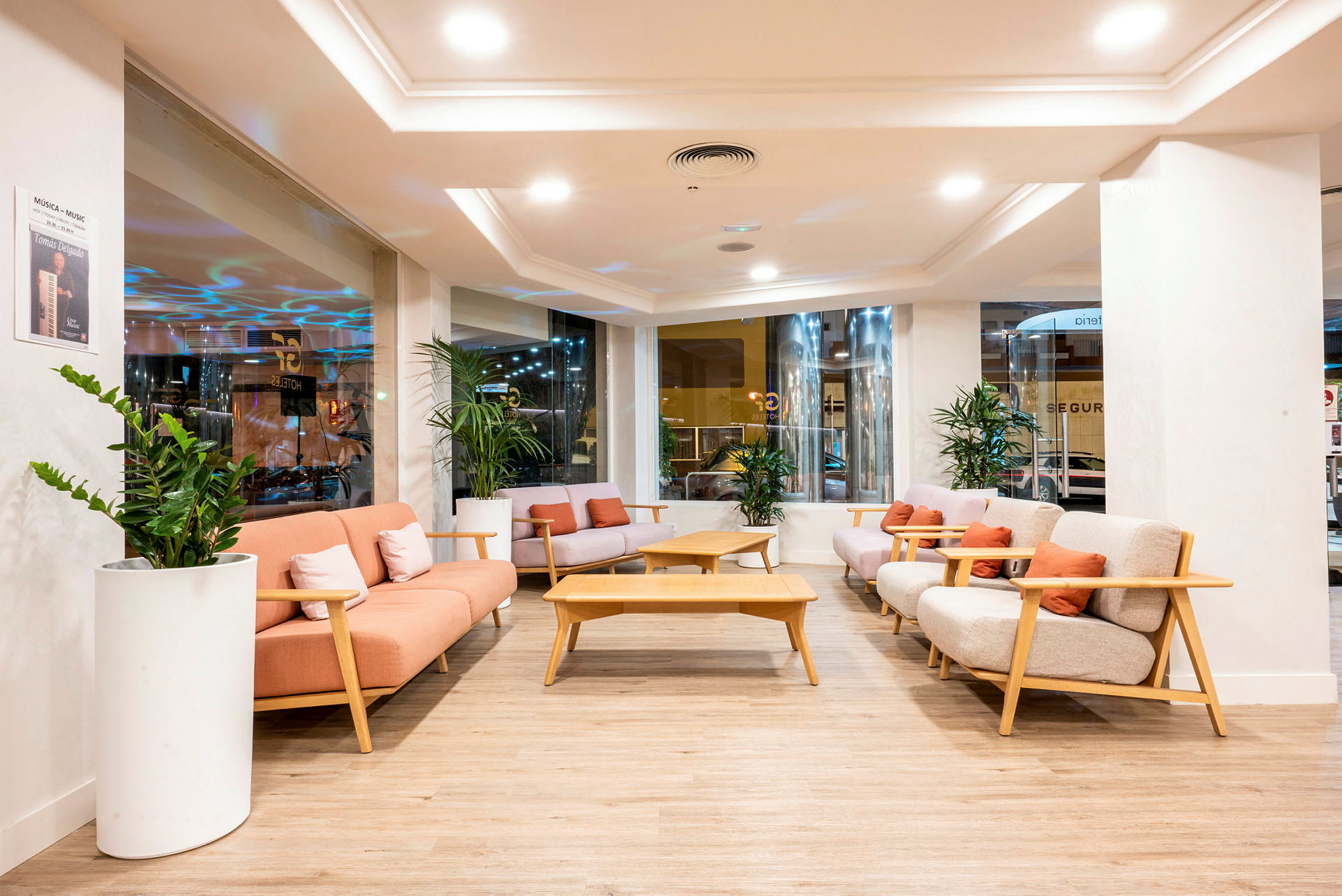 En hotellobby med komfortable sofaer, sofabord og grønne planter. (AI-generert tekst)