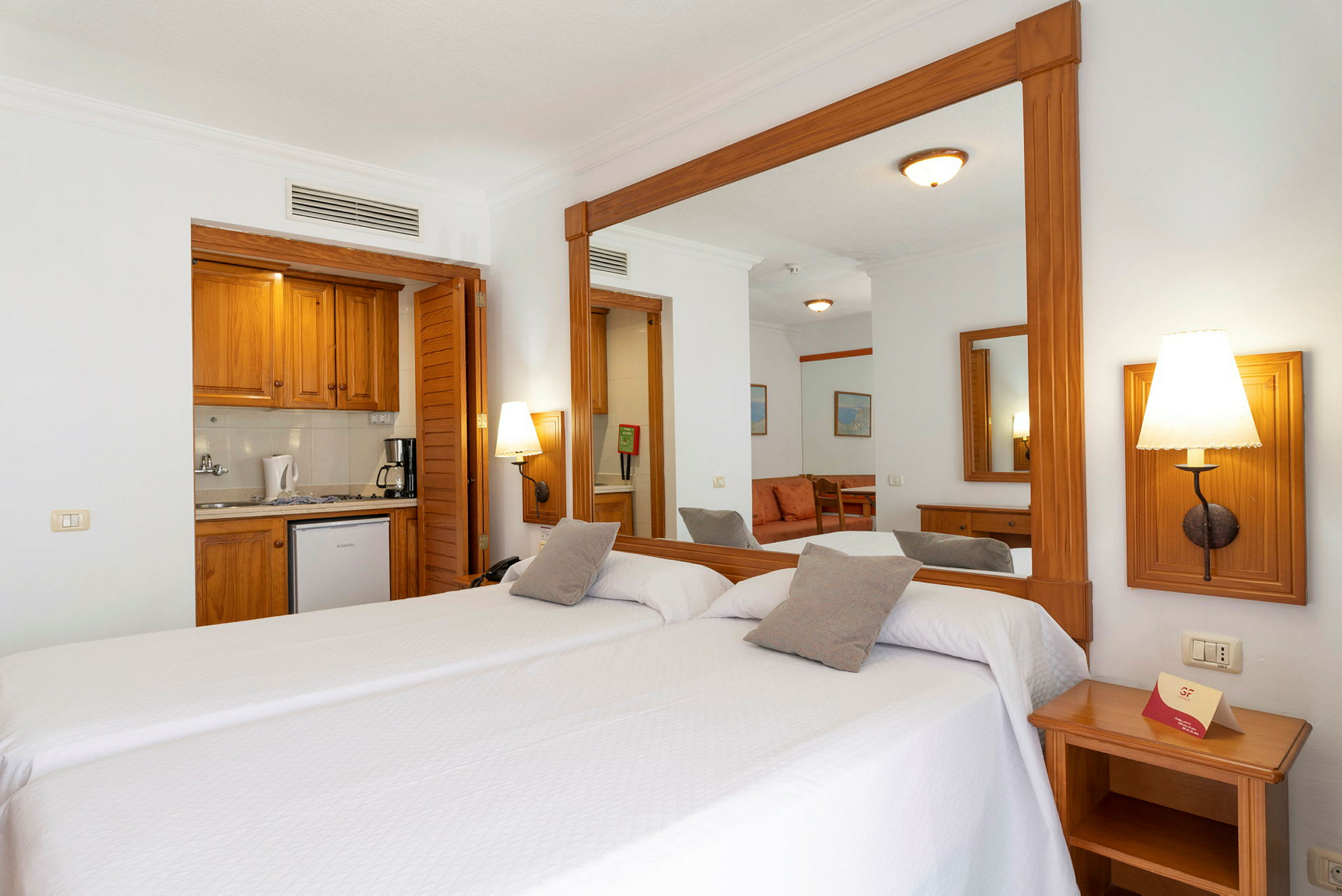 Hotellrom med to enkeltsenger og et speil. (AI-generert tekst)