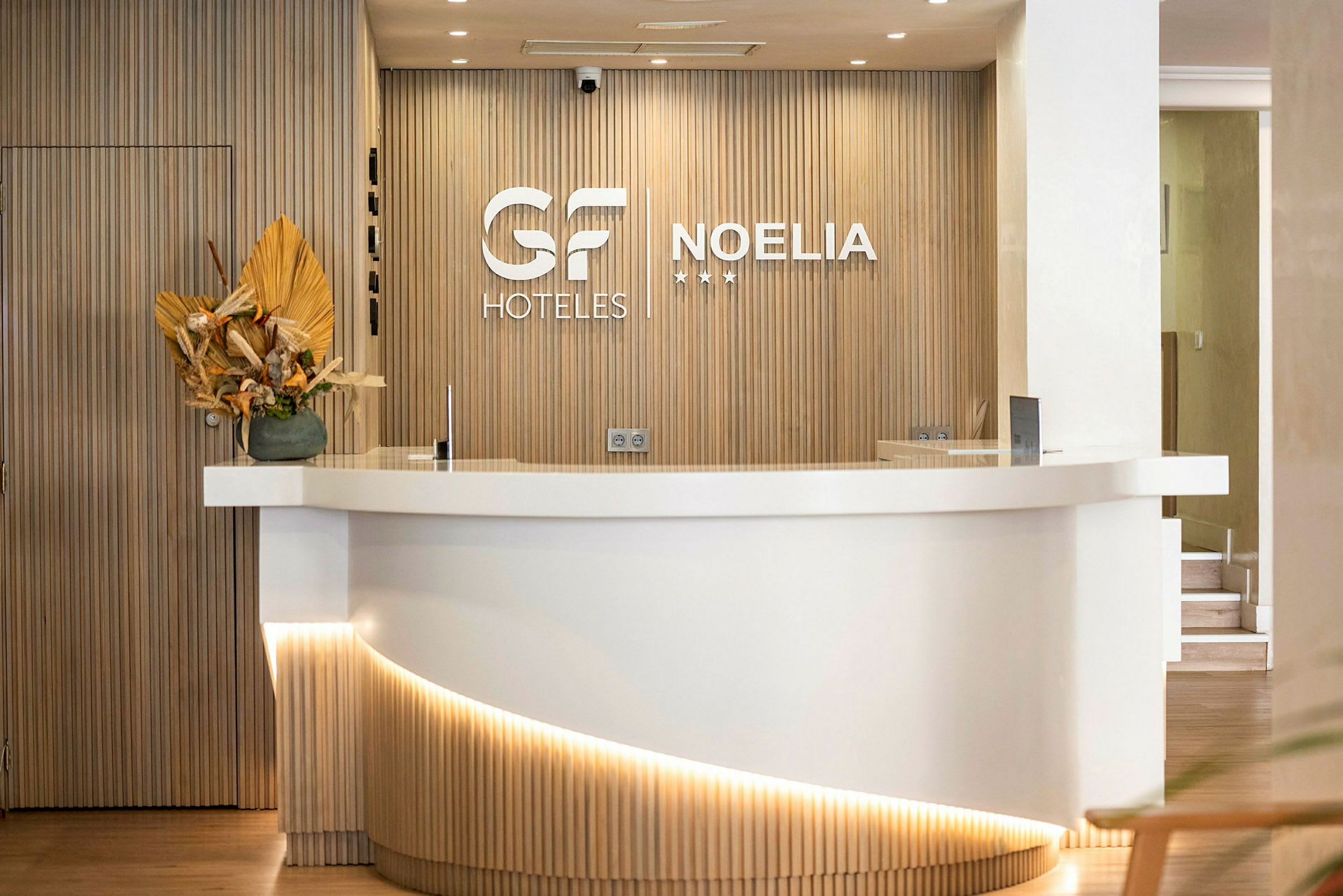 Hotellresepsjon med en hvit disk og en trevegg med logoer. (AI-generert tekst)