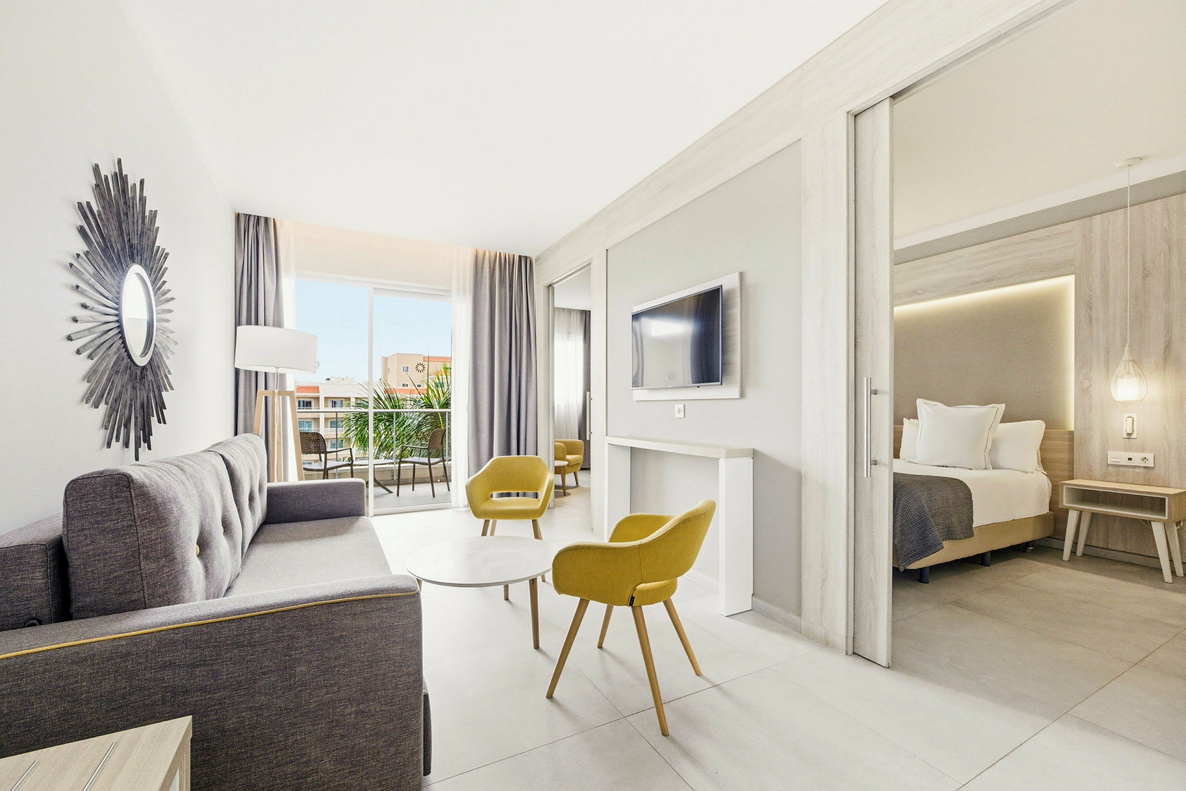 Lyst og moderne hotellrom med sittegruppe, soverom og balkong. (AI-generert tekst)