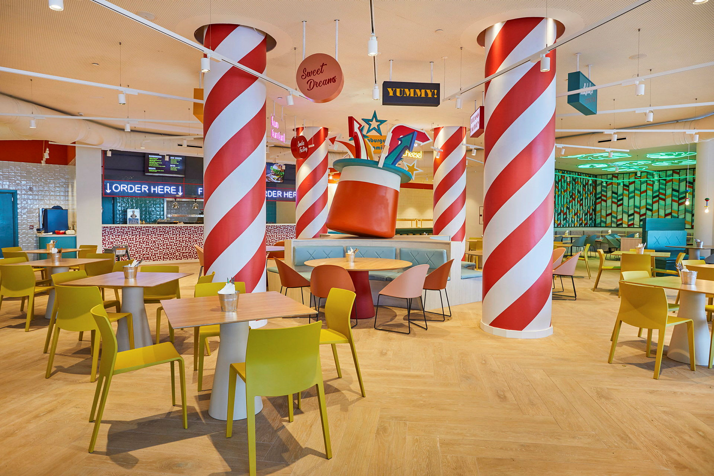 Restaurant med fargerik innredning, bord og stoler samt dekorative stolper. (AI-generert tekst)