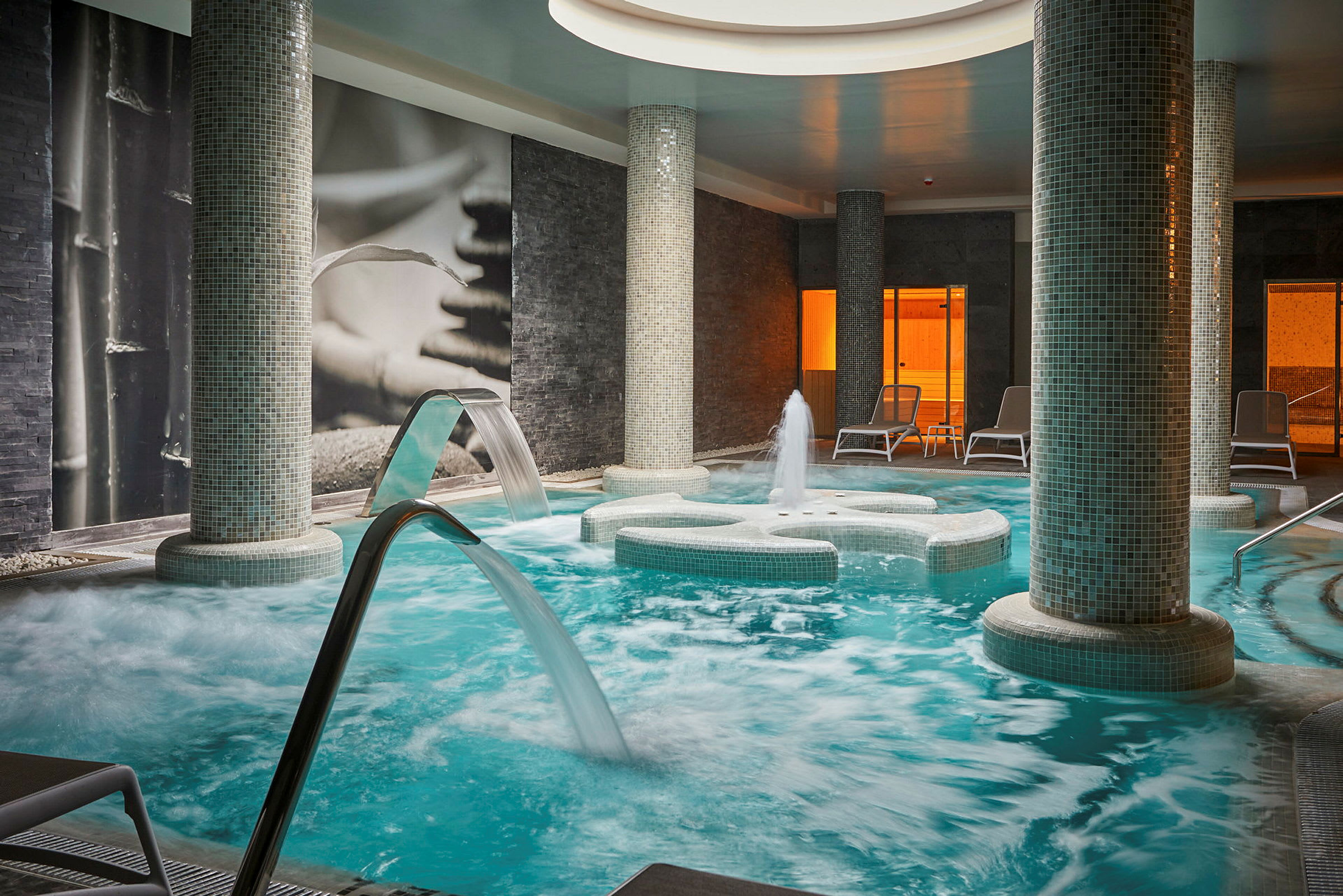 Innendørs spa med basseng, vannstråler og lounge-stoler. (AI-generert tekst)