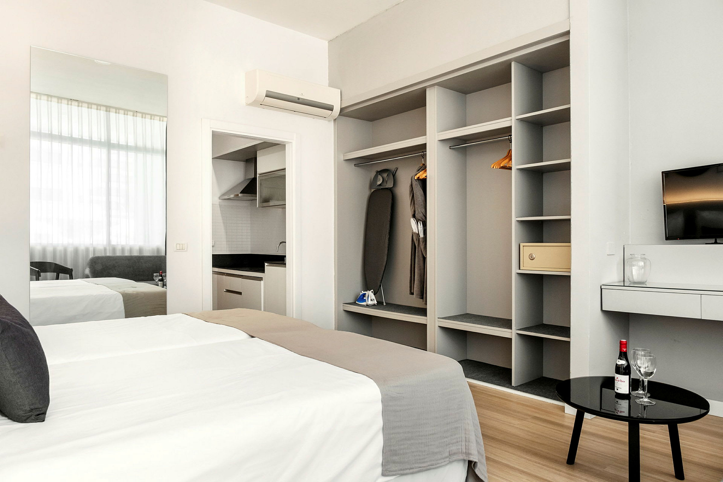 Moderne hotellrom med seng, garderobe, en TV og kjøkkenkrok. (AI-generert tekst)