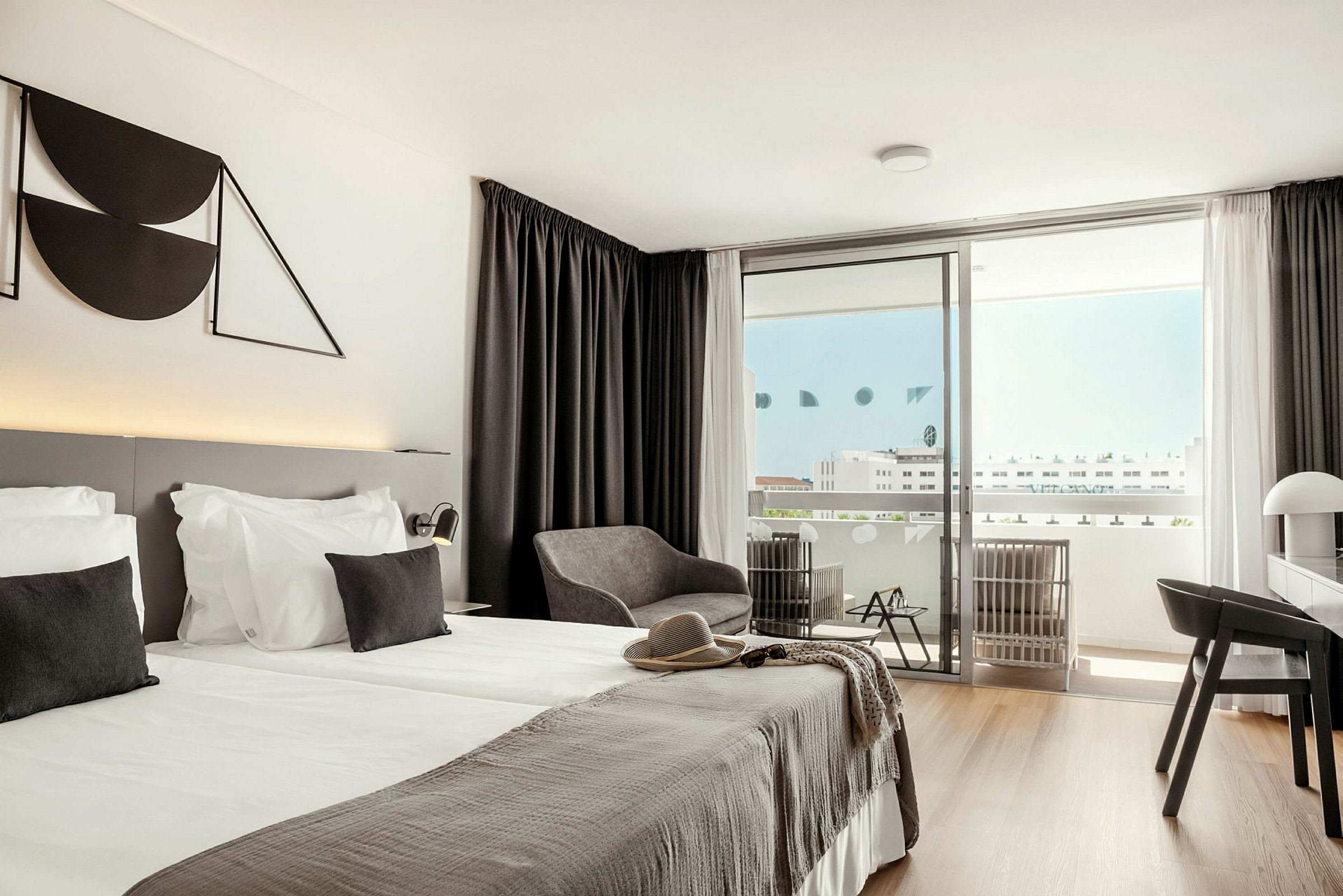 Et moderne hotellrom med dobbeltseng, sitteområde og balkong. (AI-generert tekst)