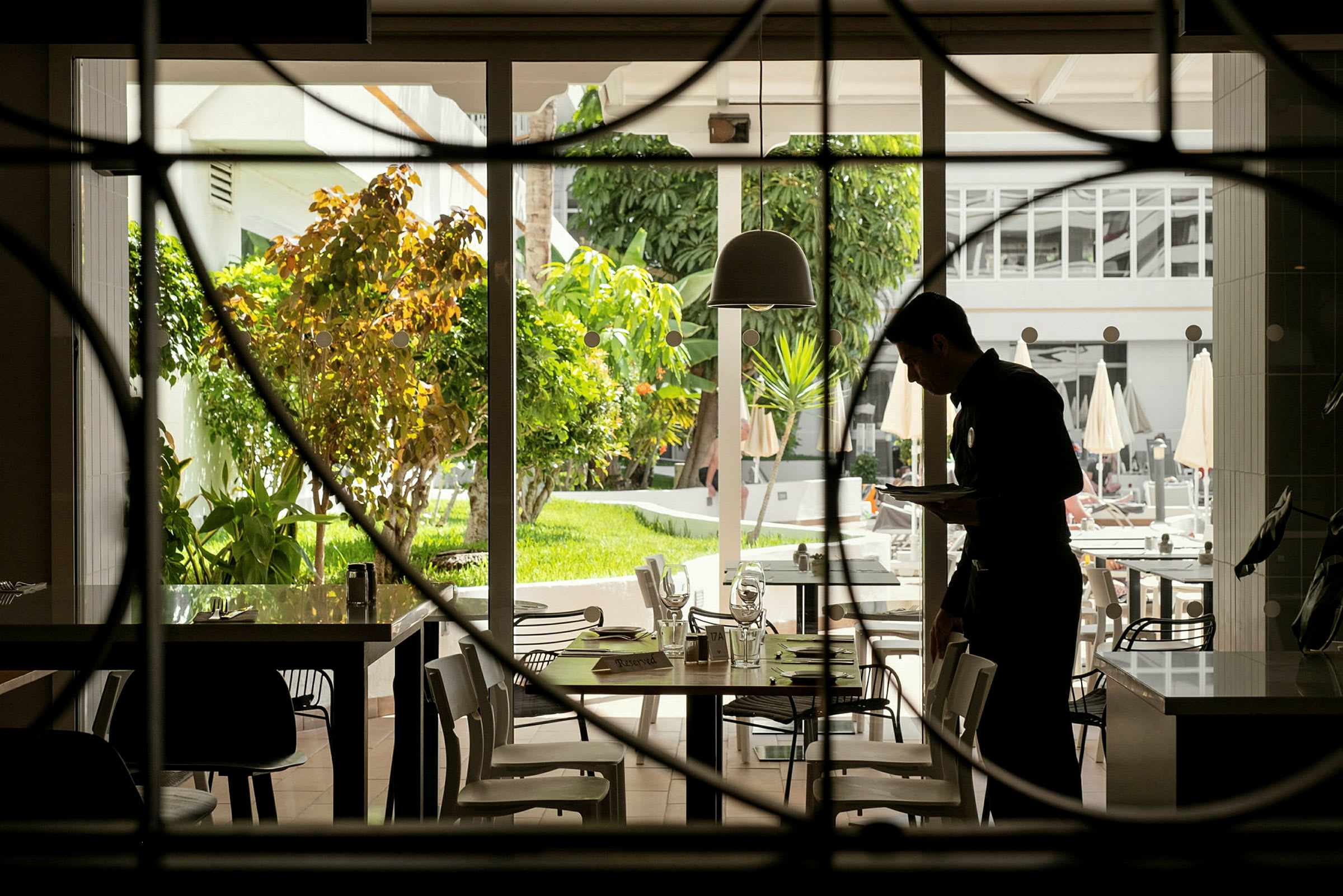 Et restaurantområde med et bord som vender mot en utendørs hage. (AI-generert tekst)