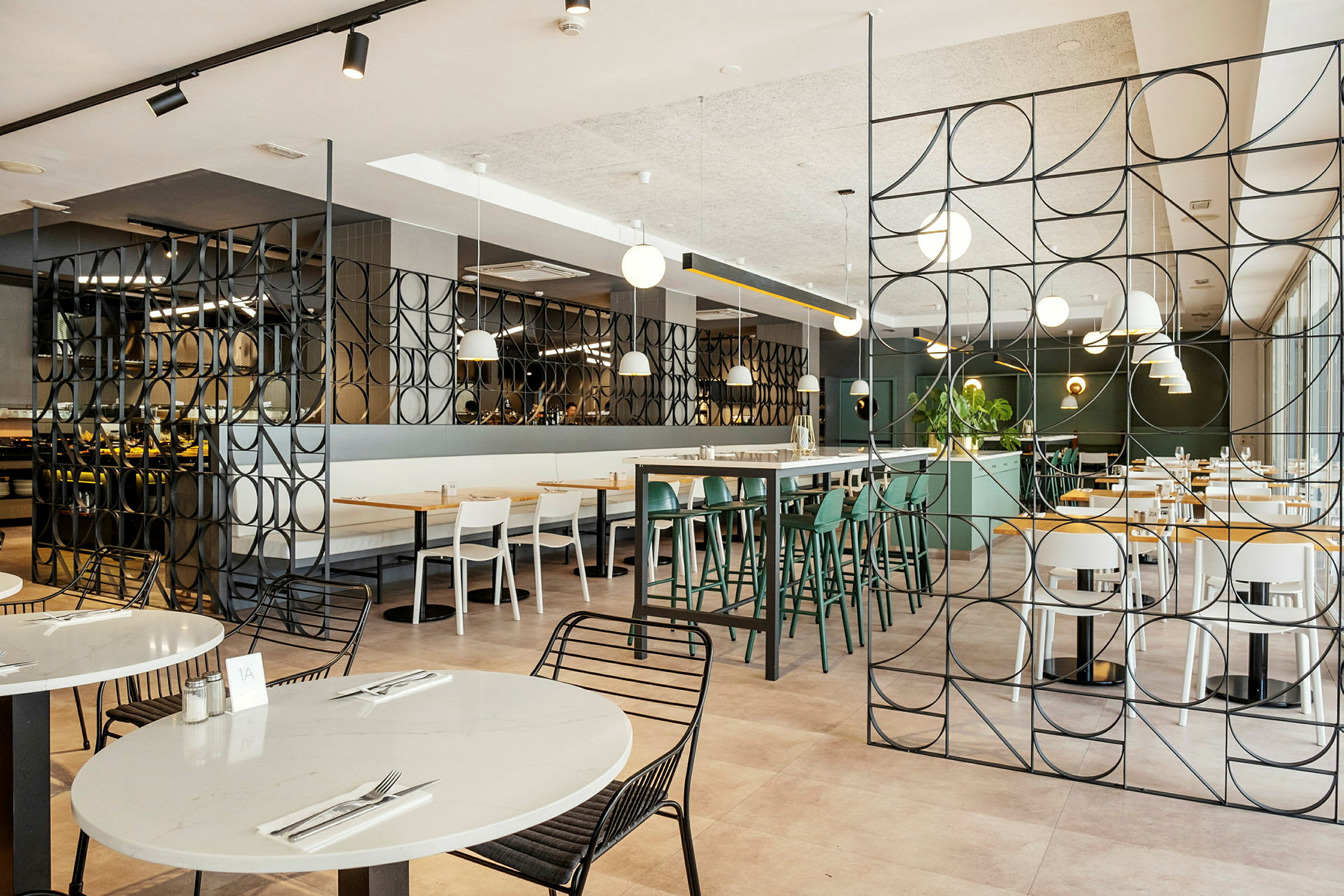 Interiør av en moderne restaurant med bord og stoler samt dekorative metallpaneler. (AI-generert tekst)