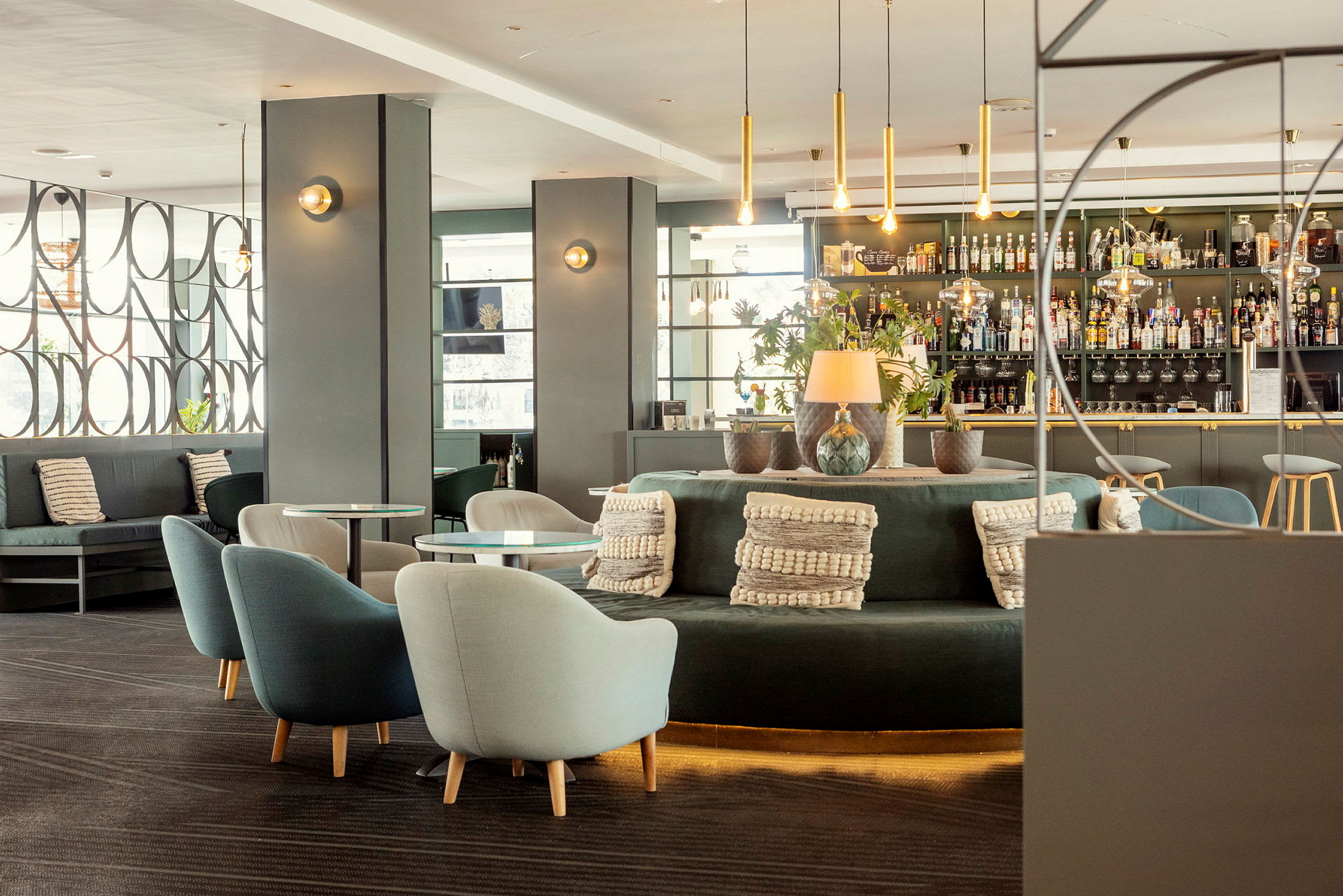 Moderne innredet hotellbar med sittegrupper, dekorasjoner og hyller med flasker. (AI-generert tekst)