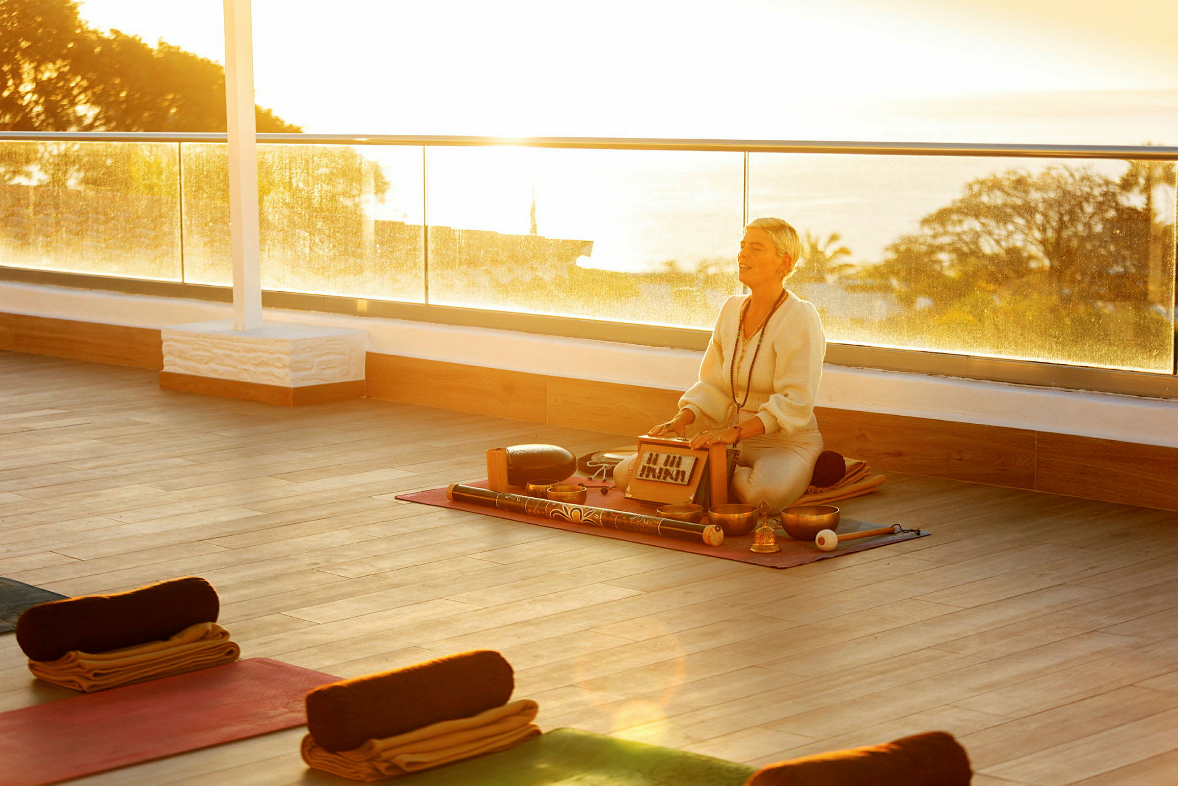Person med instrument på yogamatte i solnedgang. (AI-generert tekst)