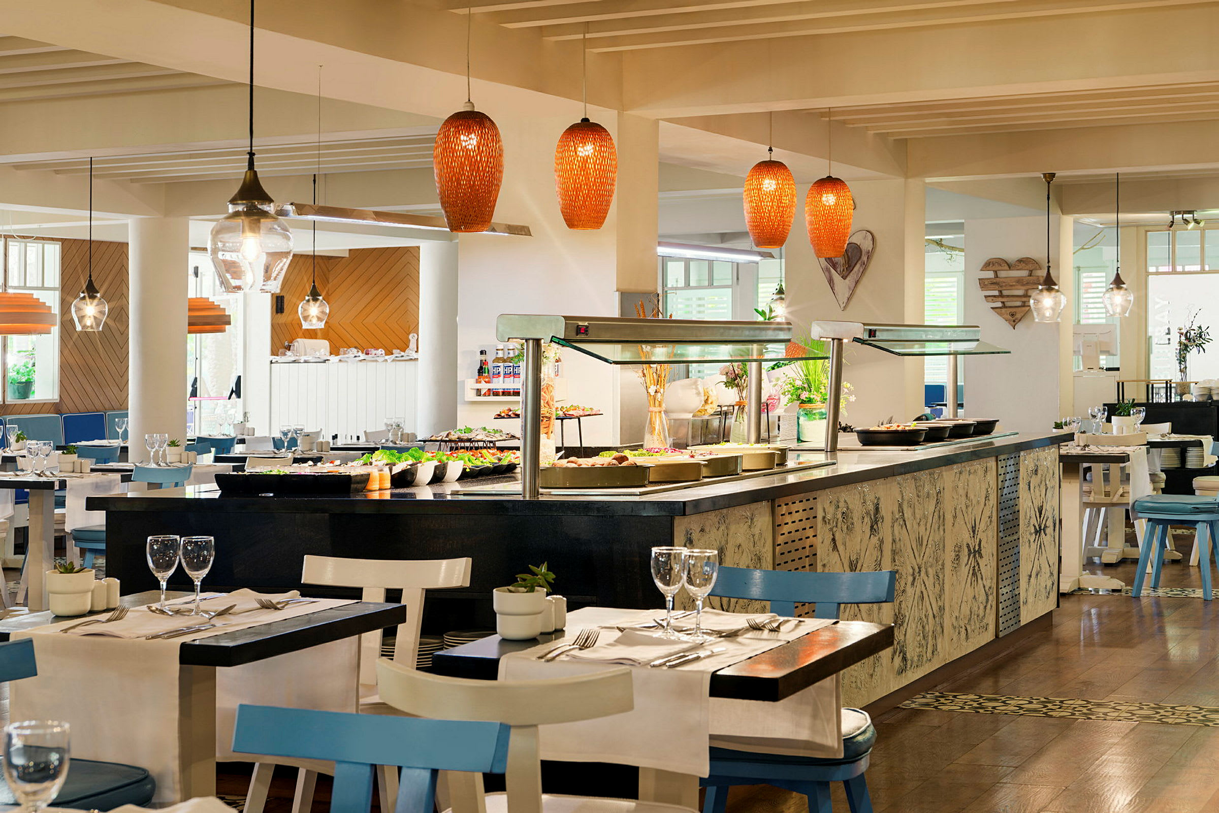 Interiør av en restaurant med dekkede bord og et serveringsområde med salater og andre matalternativer. (AI-generert tekst)