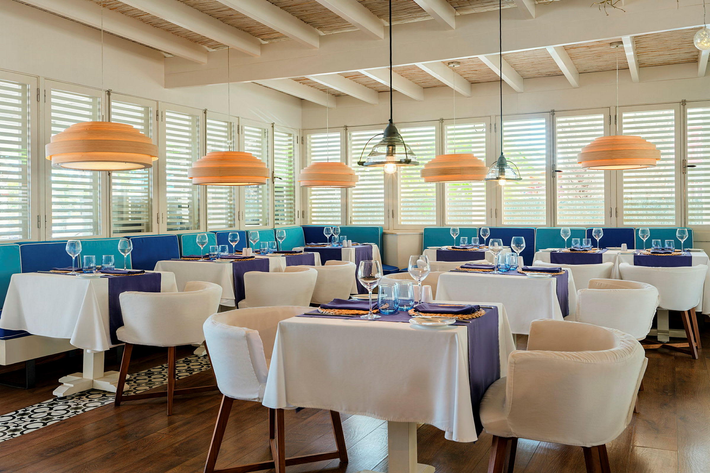 En elegant restaurant med hvite duker, blå dekor og moderne taklamper. (AI-generert tekst)
