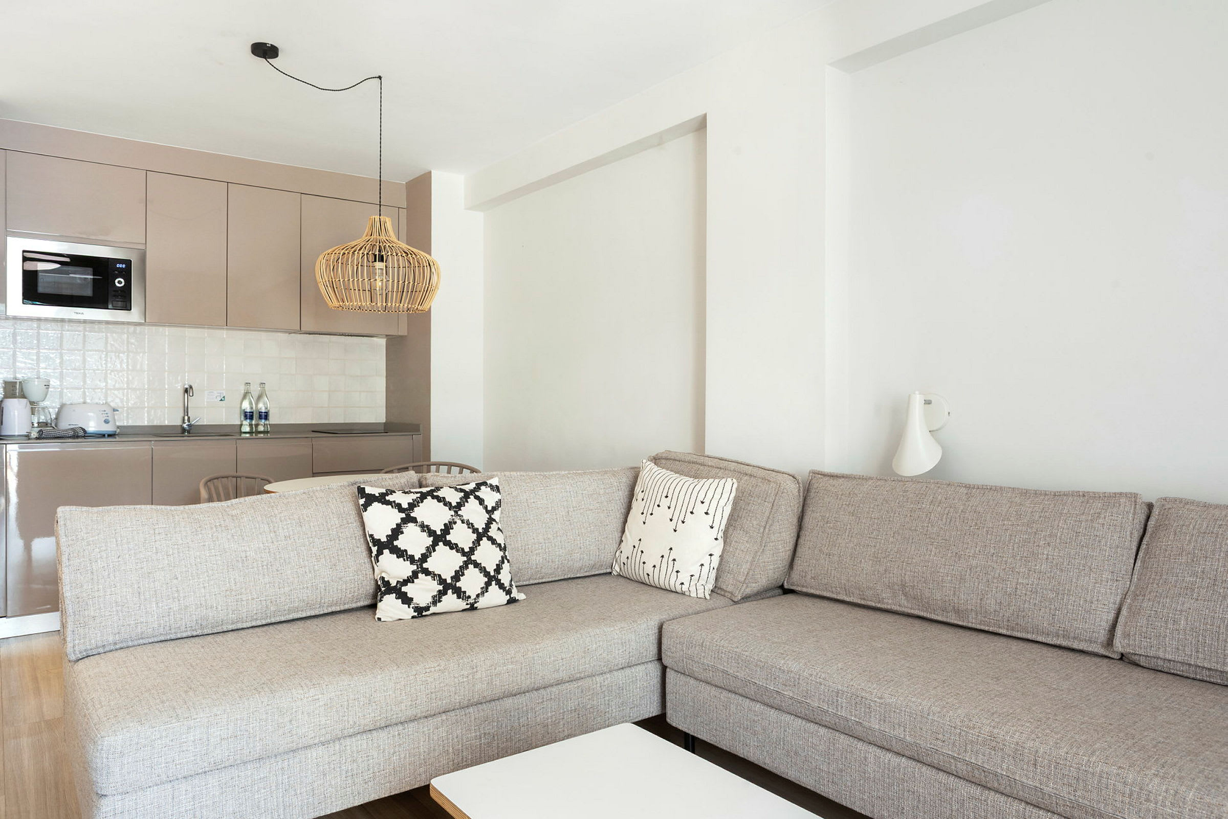 En stue med en beige sofa og kjøkkendel i bakgrunnen. (AI-generert tekst)