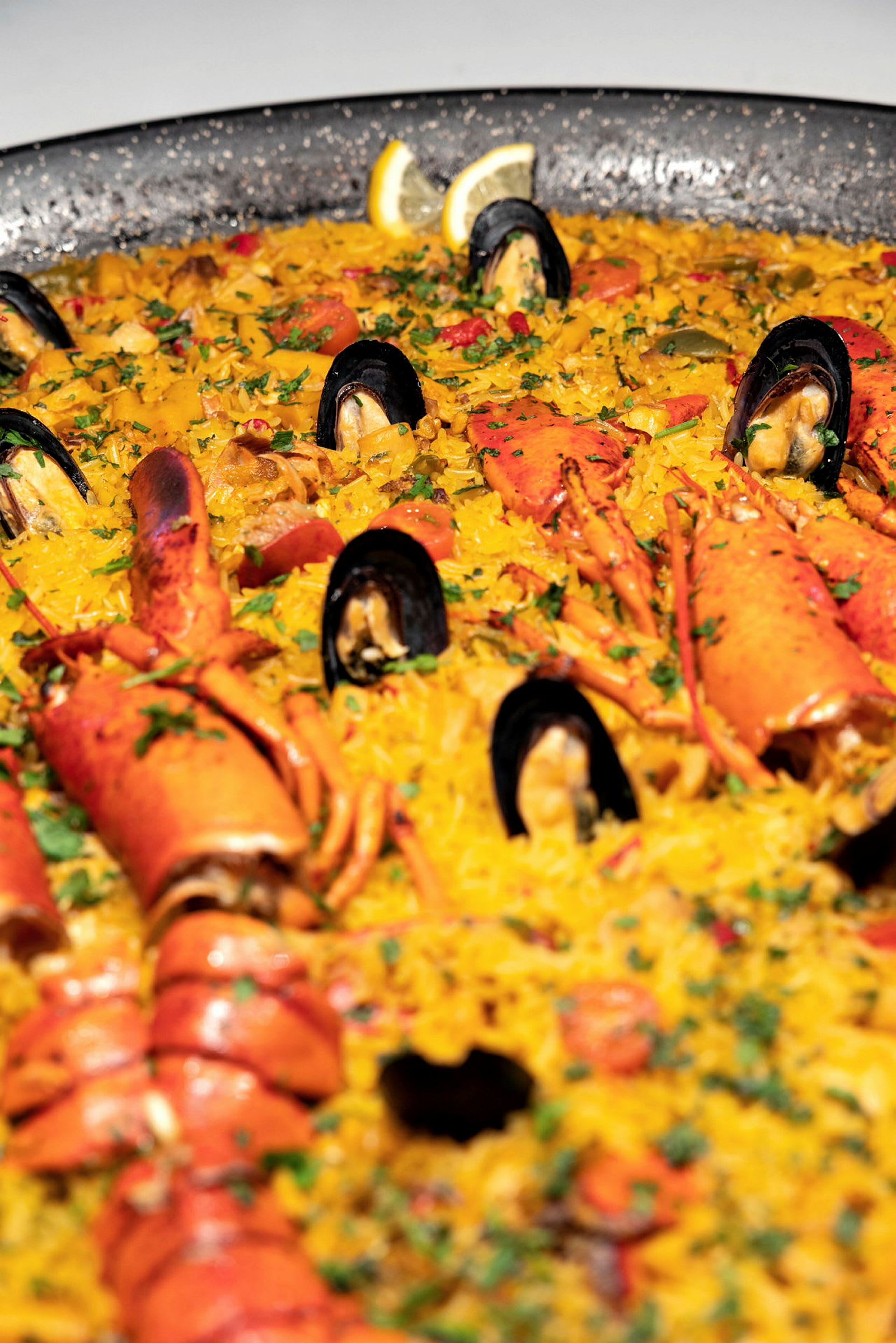 En stor paella med skalldyr, inkludert blåskjell og hummer, er servert. (AI-generert tekst)
