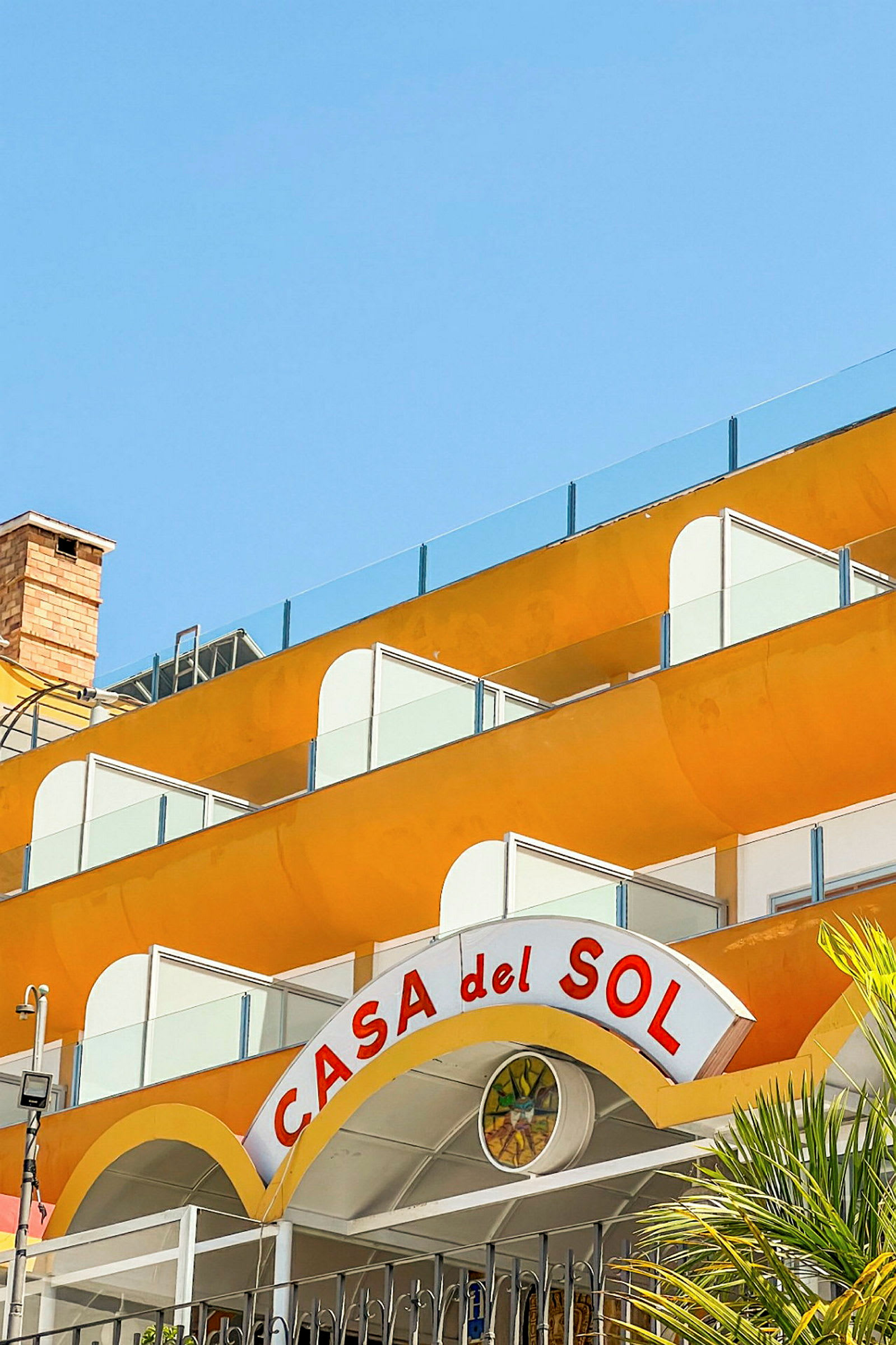 En bygning med gule balkonger og et skilt med teksten "Casa del Sol". (AI-generert tekst)