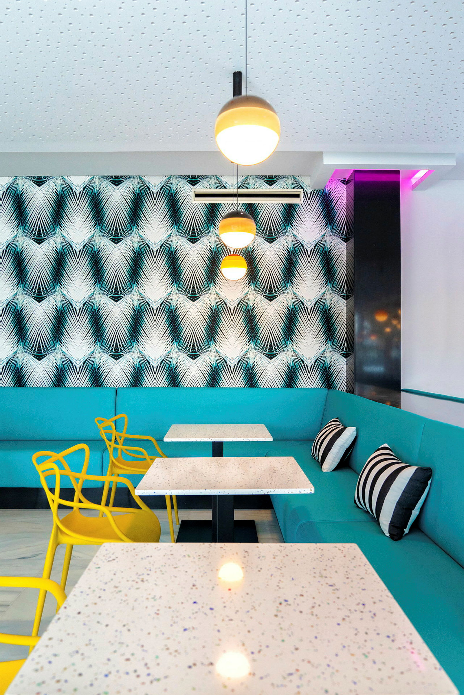 Moderne restaurantinnredning med turkise sofaer og gule stoler. (AI-generert tekst)