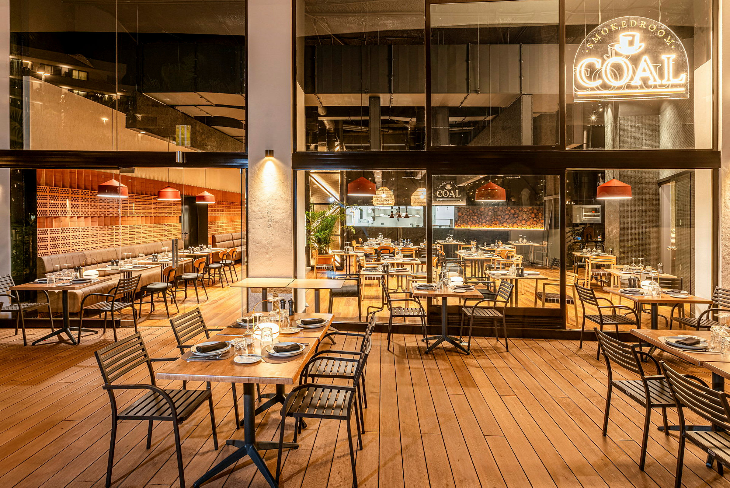 Restaurant med utendørs- og innendørs sitteplasser, dekorert med tretrekk og moderne møbler. (AI-generert tekst)