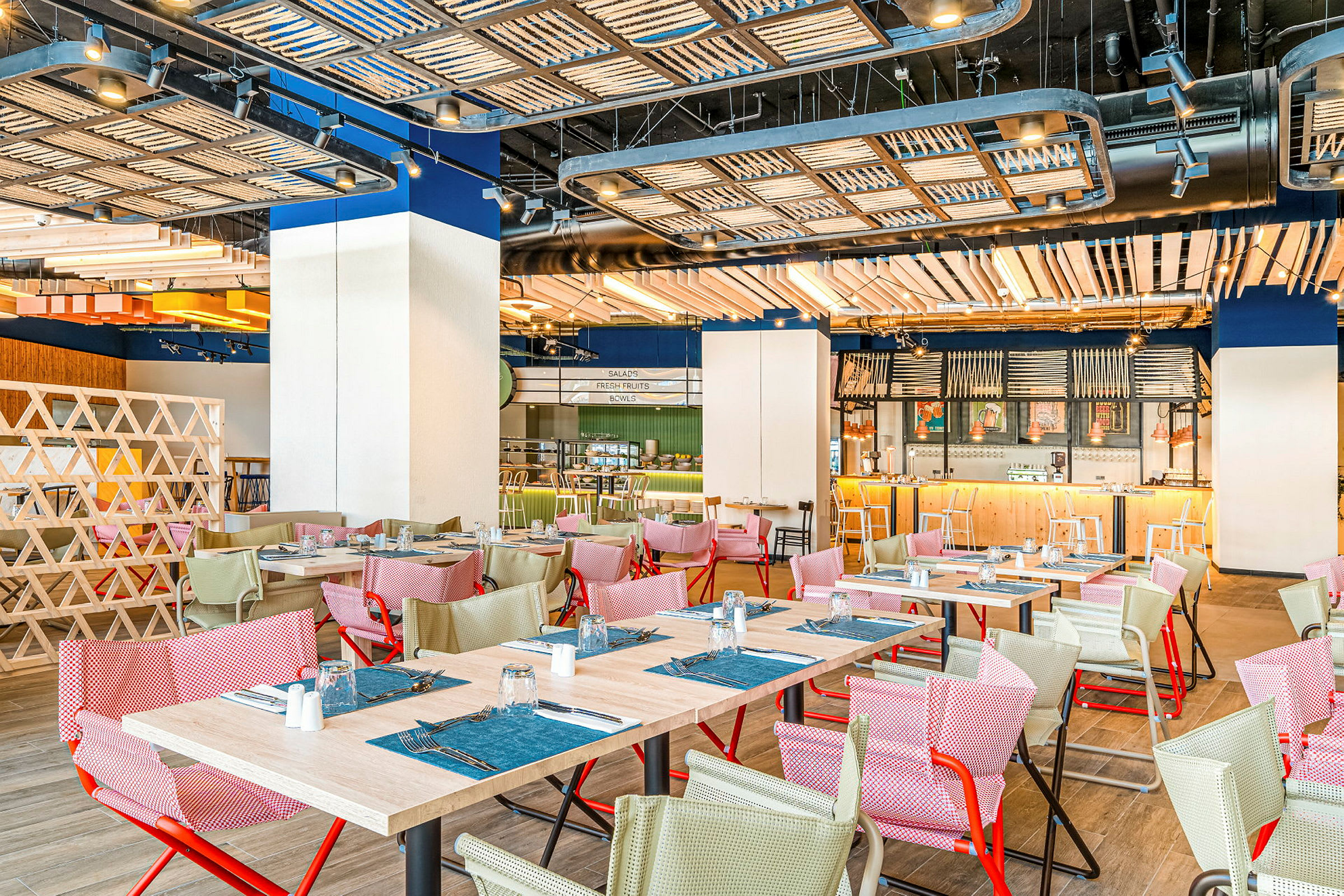 Interiørbilde av en restaurant med bord og stoler i forskjellige farger samt en åpen planløsning. (AI-generert tekst)