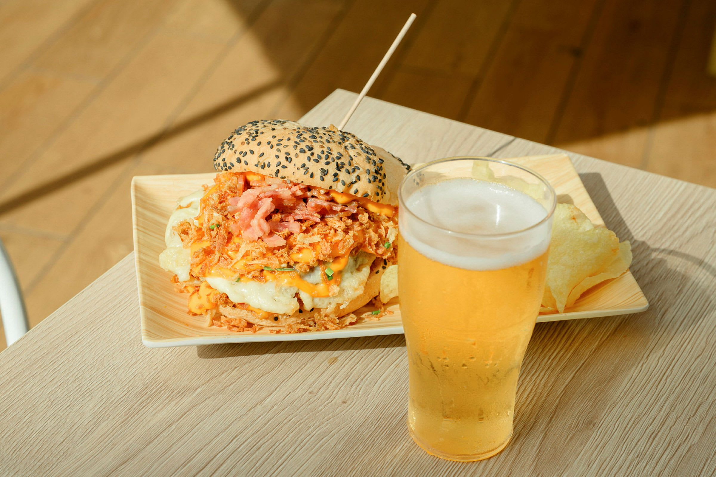 En tallerken med en burger med mye fyll ved siden av et glass øl på et bord. (AI-generert tekst)