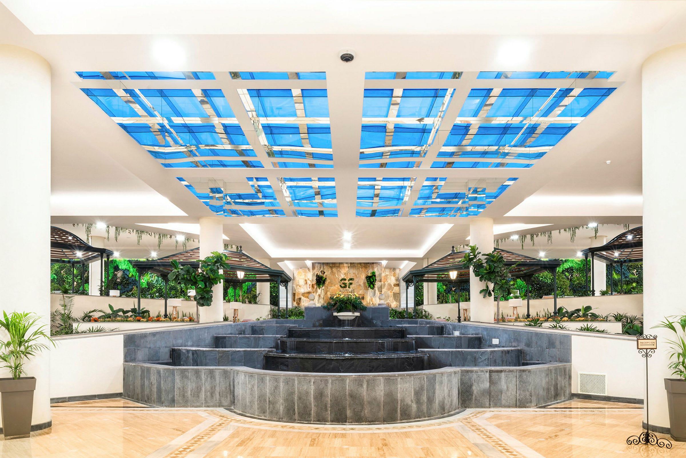 En lys og åpen hotellobby med fontene og frodig interiør. (AI-generert tekst)