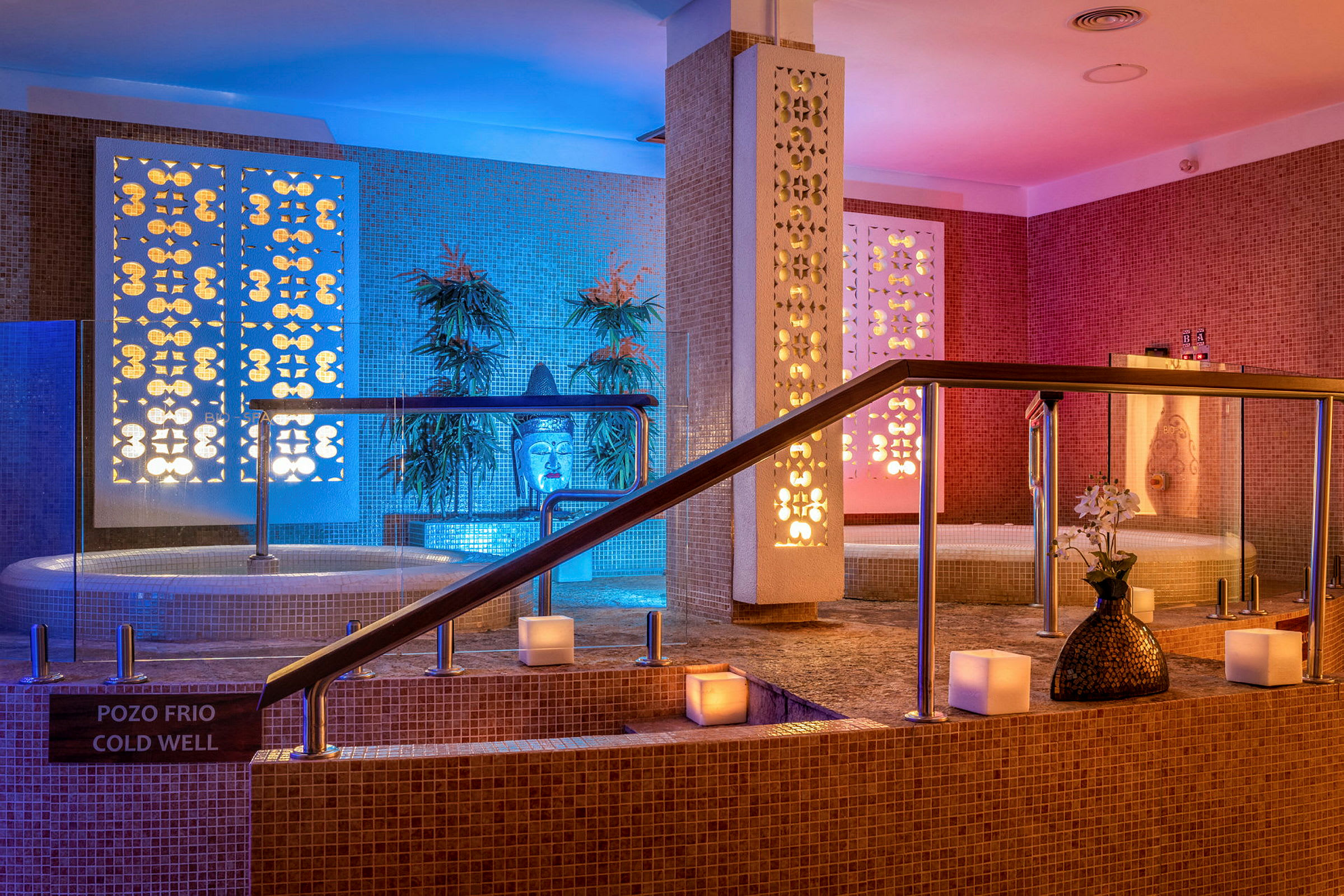 Spa-område med jacuzzi, dekorative planter og belysning i ulike farger. (AI-generert tekst)