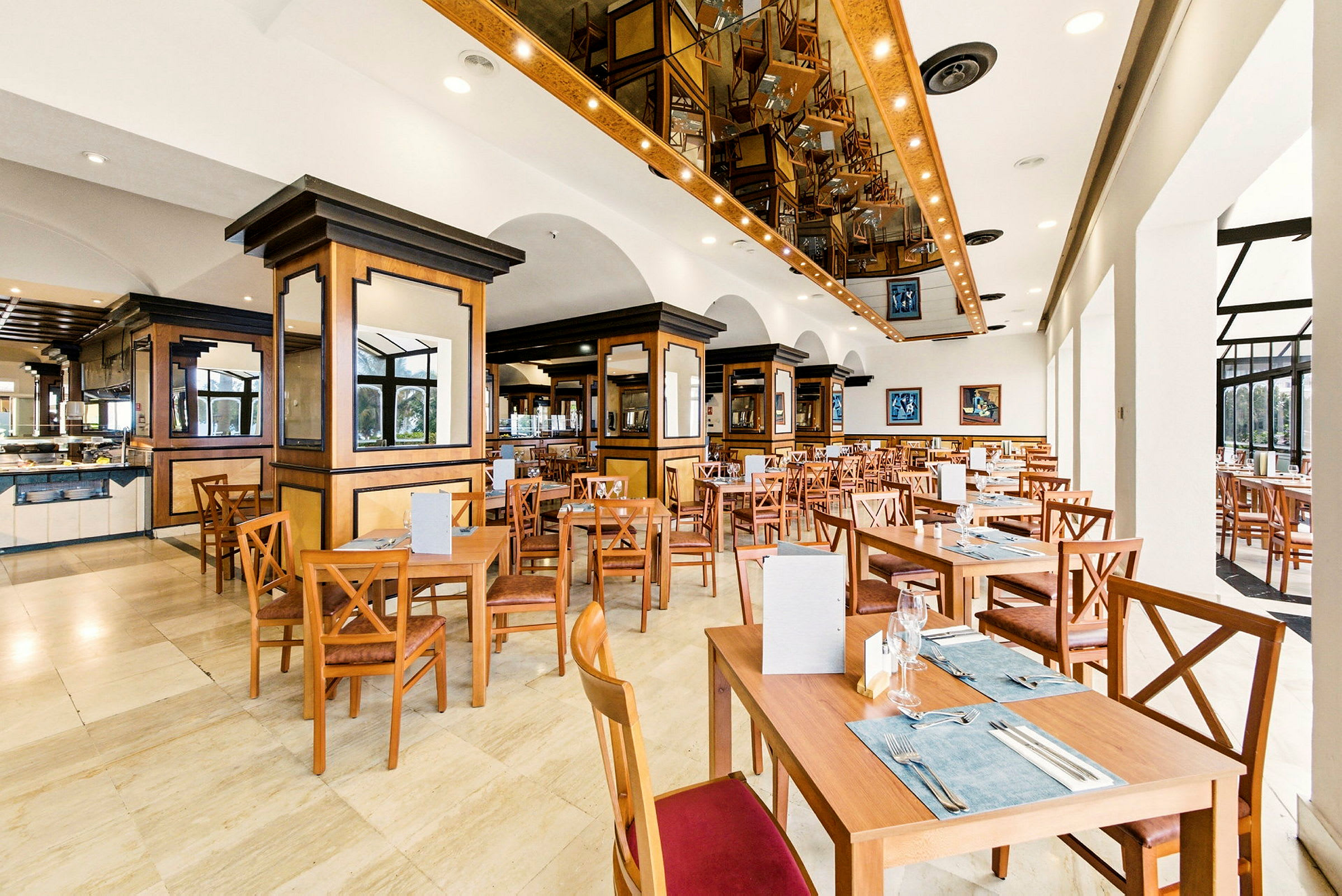 Et romslig og godt opplyst restaurantområde med treinteriør og flere oppstilte bord og stoler. (AI-generert tekst)