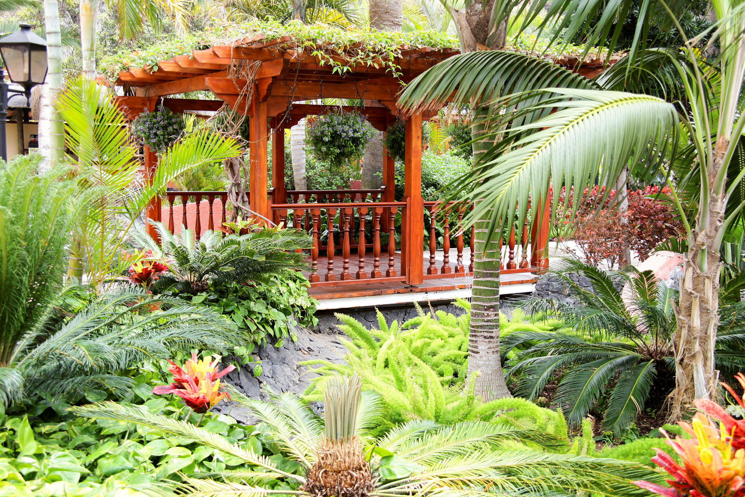 En trepaviljong omgitt av palmer og tropiske planter. (AI-generert tekst)