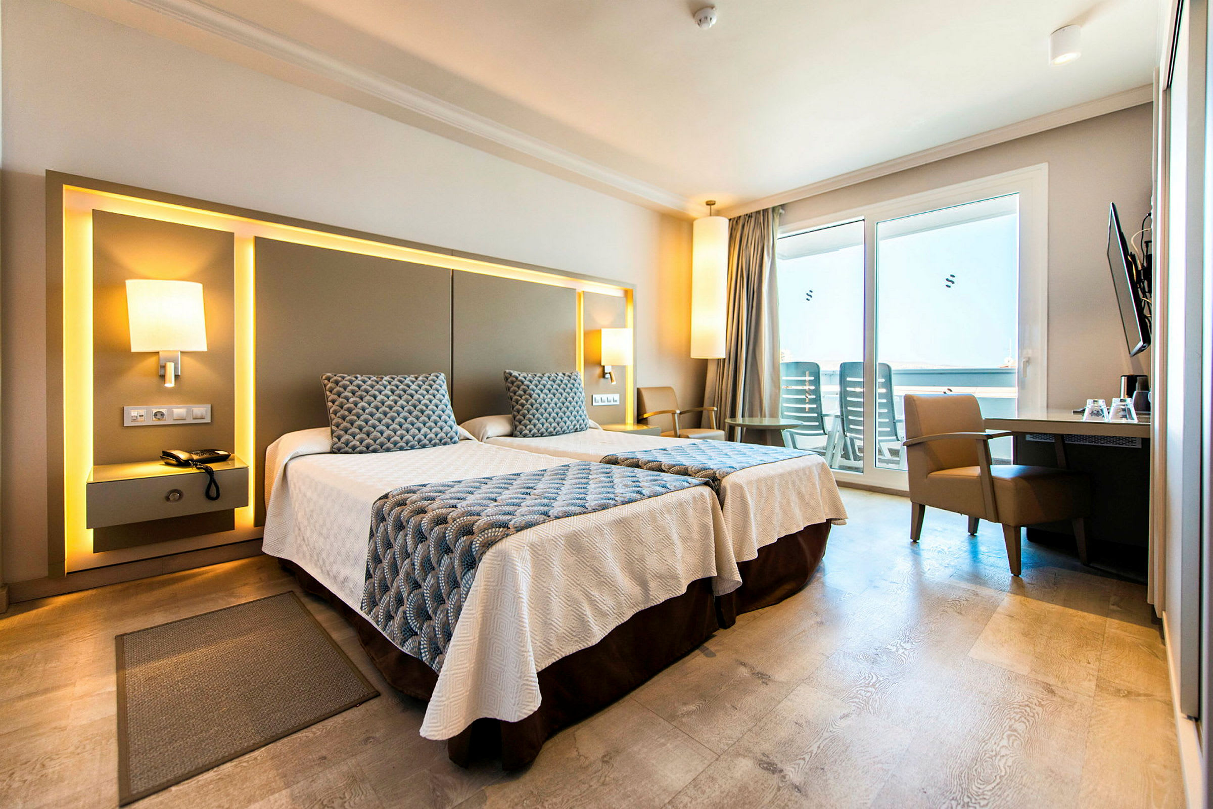 Et hotellrom med to enkeltsenger, moderne møbler og en balkong med utsikt. (AI-generert tekst)