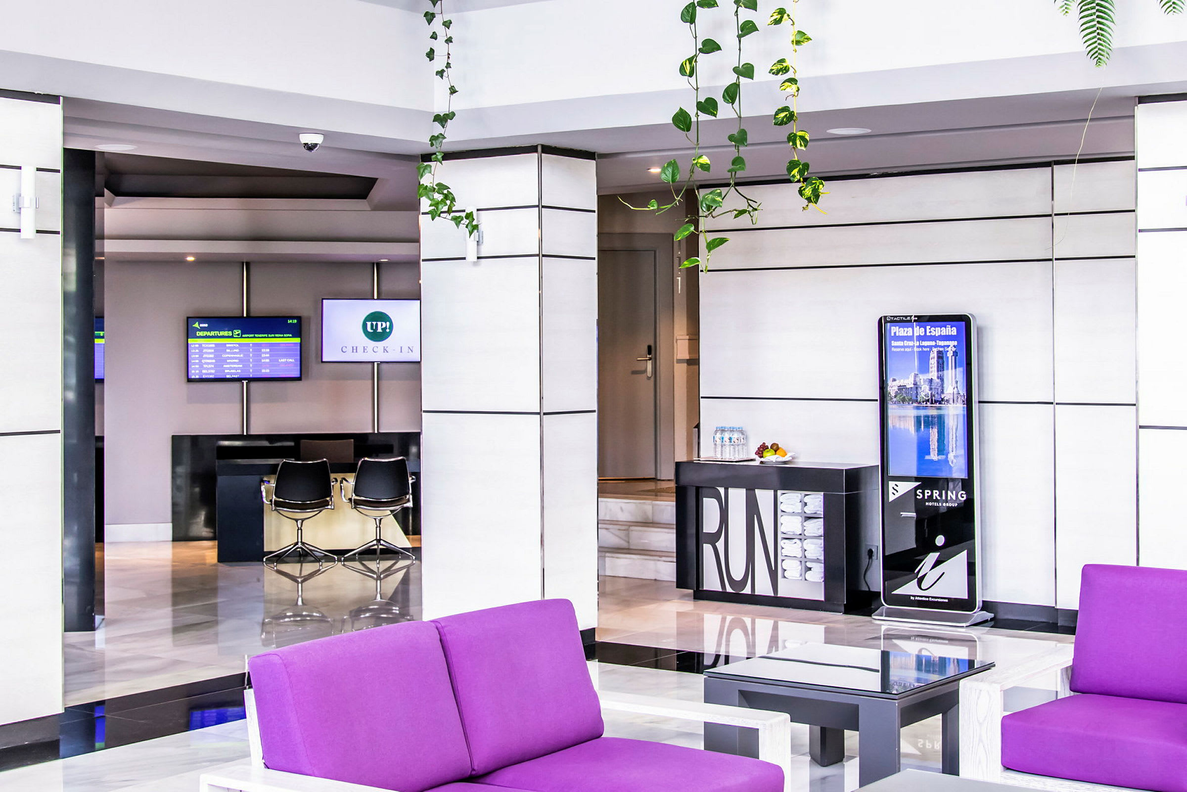 Hotellobby med innsjekkingsdisk og lilla sittemøbler. (AI-generert tekst)