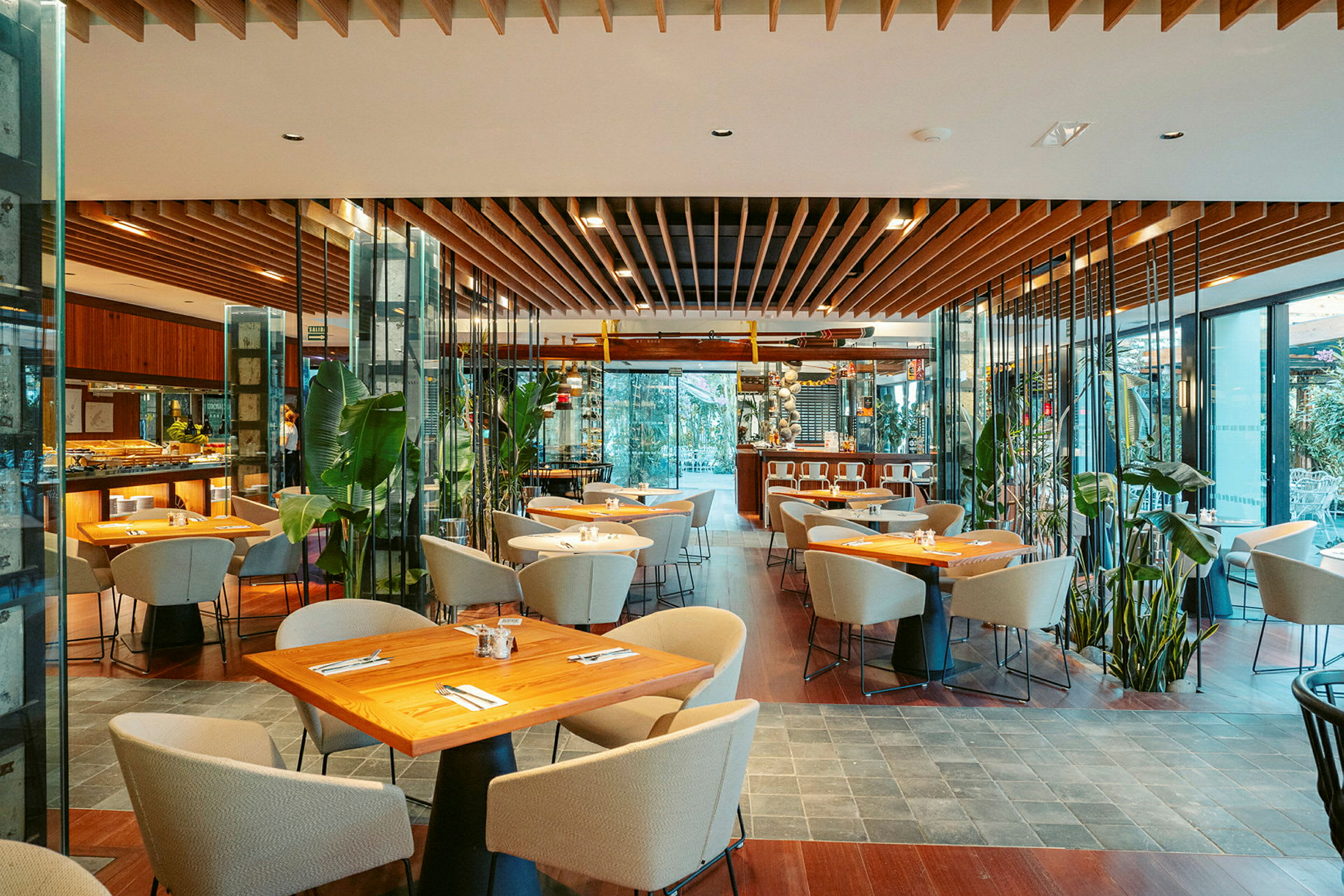 Et moderne restaurantinteriør med trebord, polstrede stoler og store plantedekorasjoner. (AI-generert tekst)