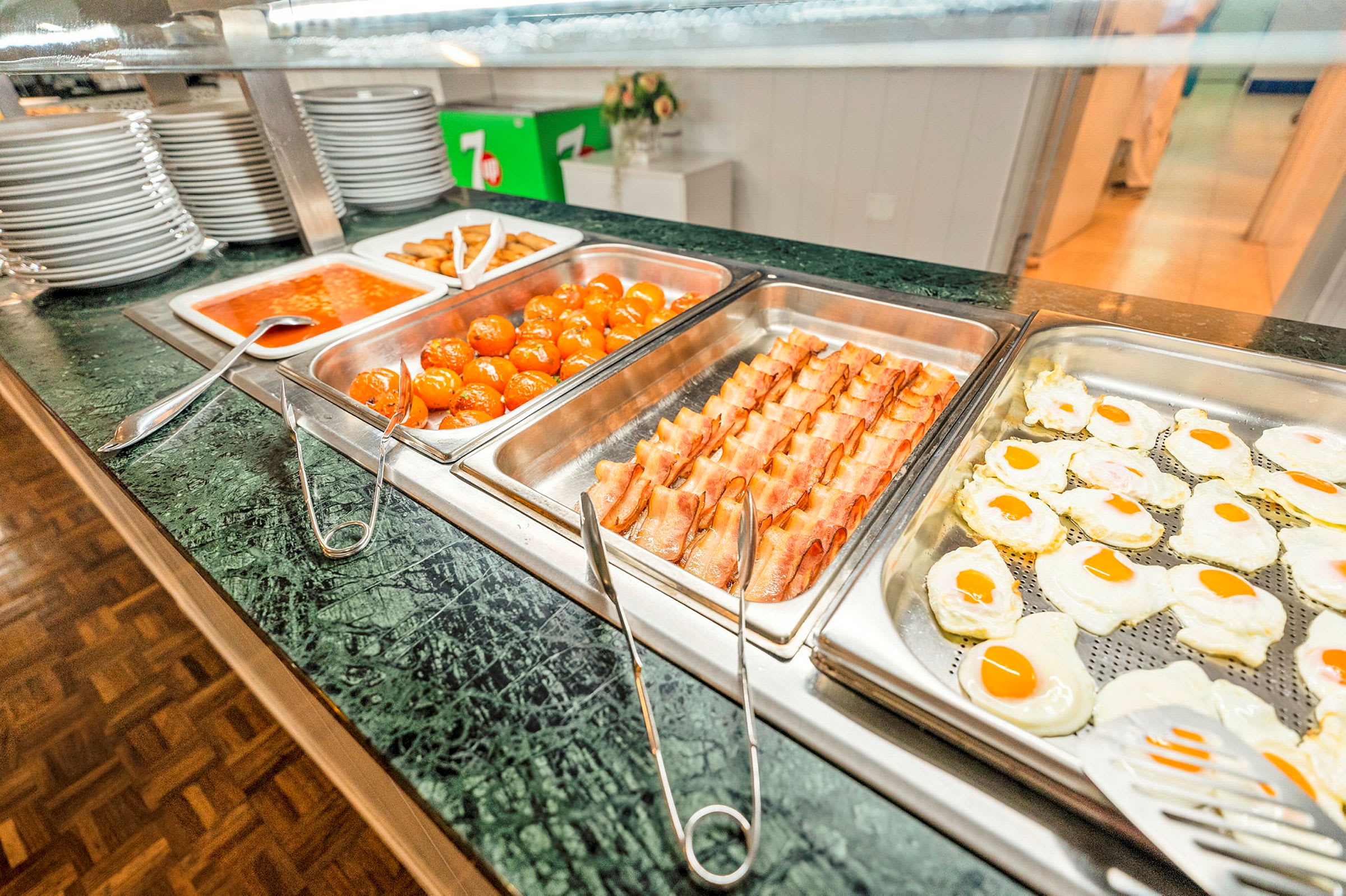 Buffetservering med ulike matretter, inkludert stekte egg, bacon, kjøttboller og tomatsaus. (AI-generert tekst)