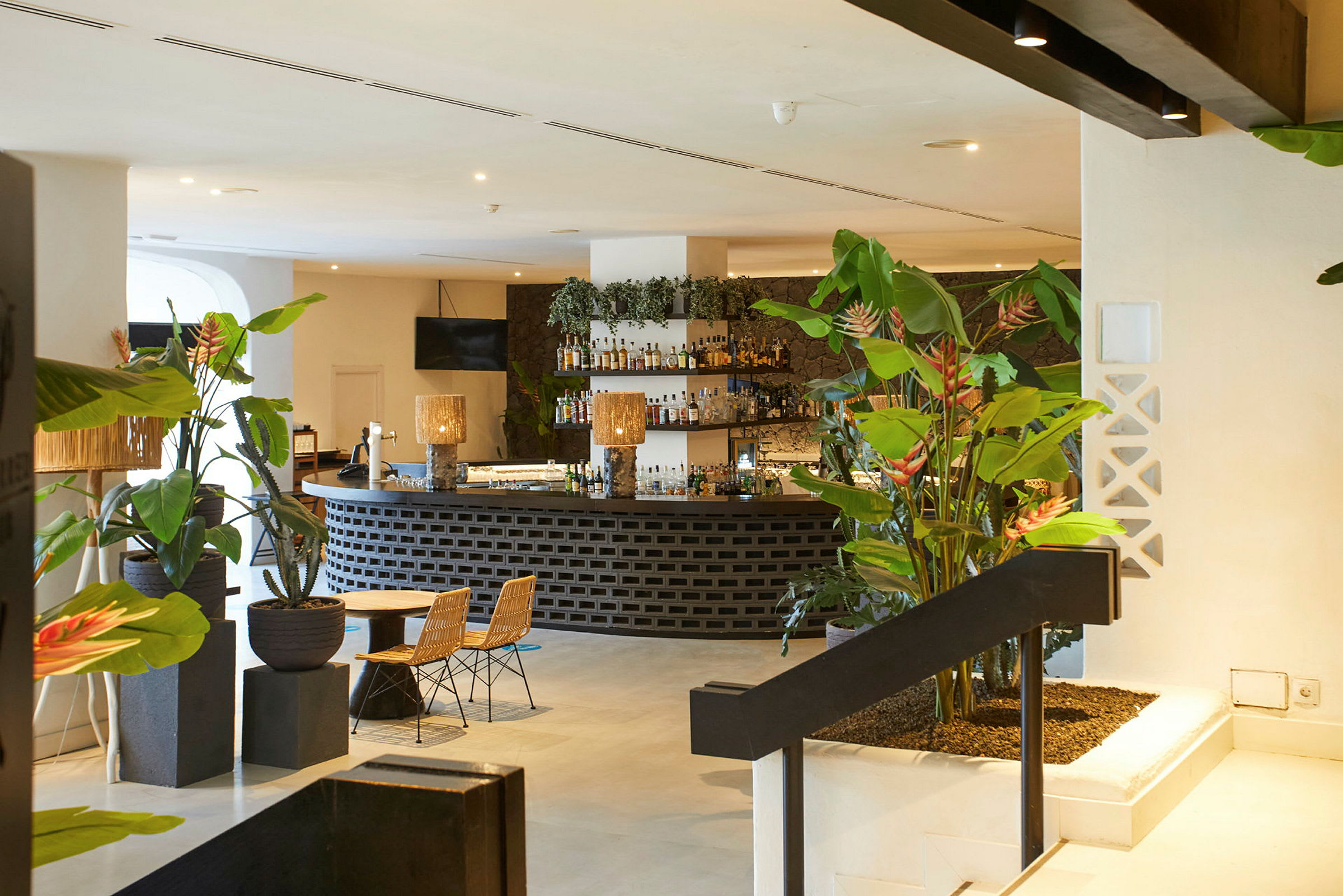 En hotellbar med plantepynt, sitteplasser og opplyst interiør. (AI-generert tekst)
