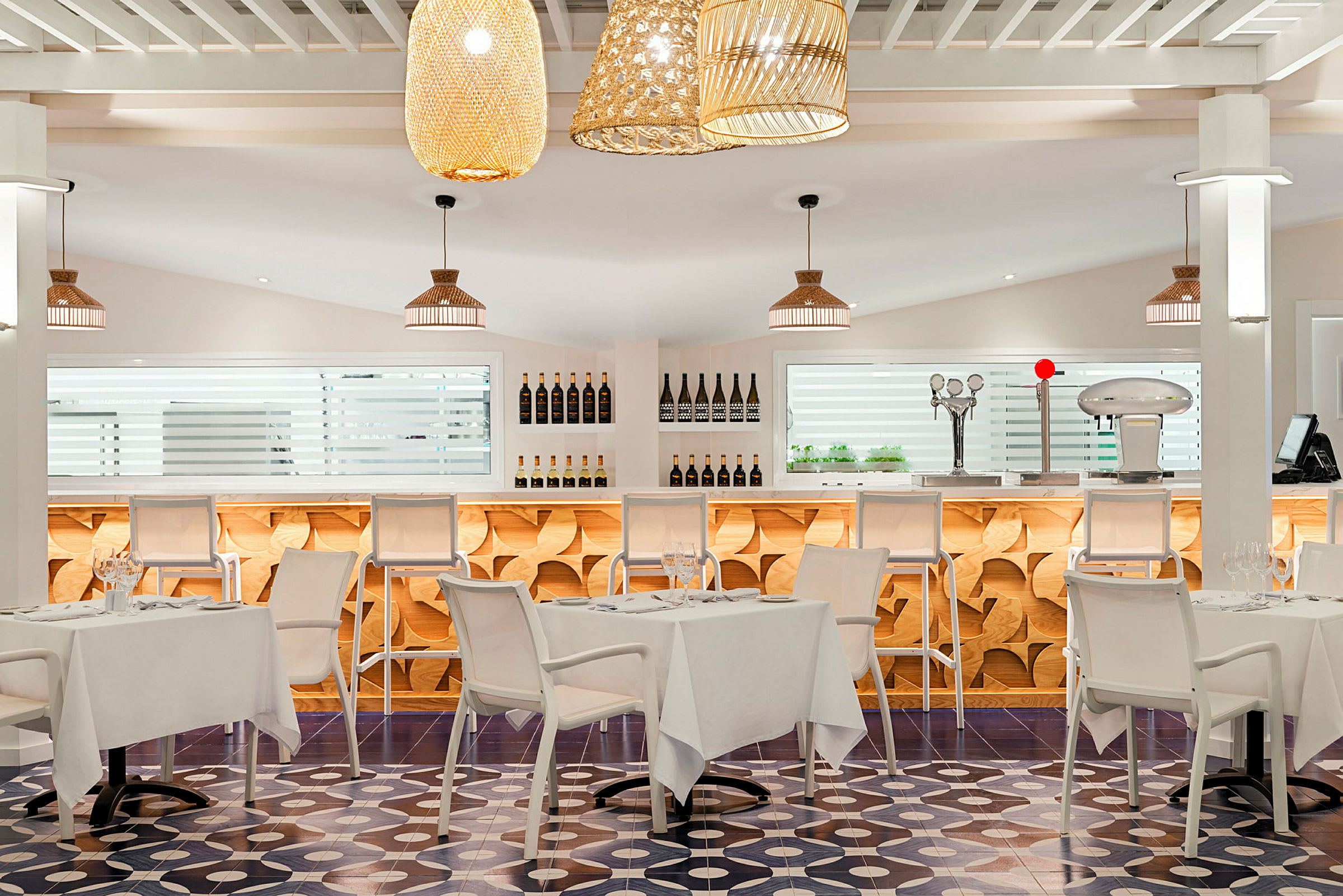 Moderne innredet restaurant med lyse farger, stilige bord og stoler samt bar i bakgrunnen. (AI-generert tekst)