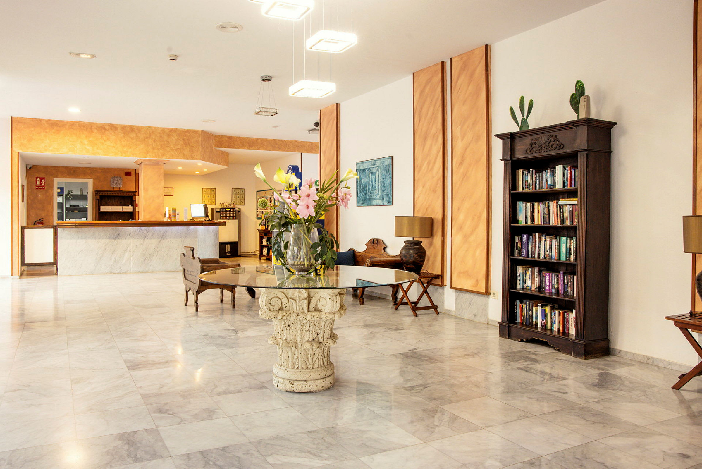 Hotellobby med resepsjonsdisk, blomsterbukett på et bord og bokhylle. (AI-generert tekst)