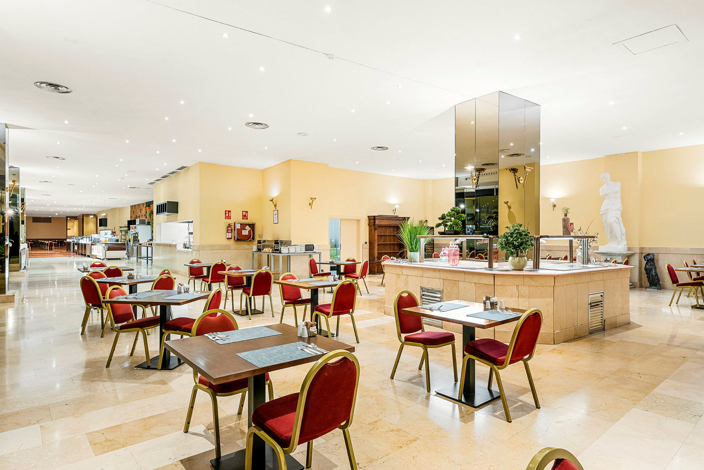Restaurant med bord og stoler plassert i et romslig og lyst innredet område. (AI-generert tekst)