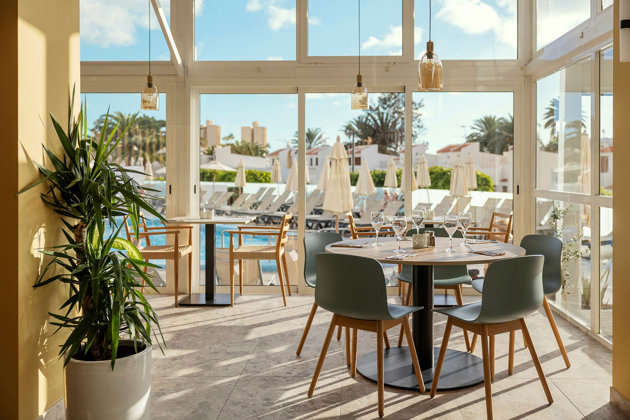 Restaurant med dekkede bord og utsikt over basseng og solsenger. (AI-generert tekst)
