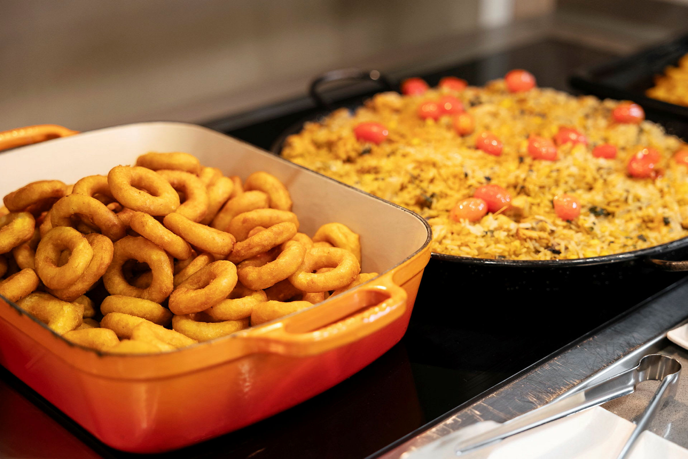 Et bilde av en buffet med løkringer og gul risrett. (AI-generert tekst)